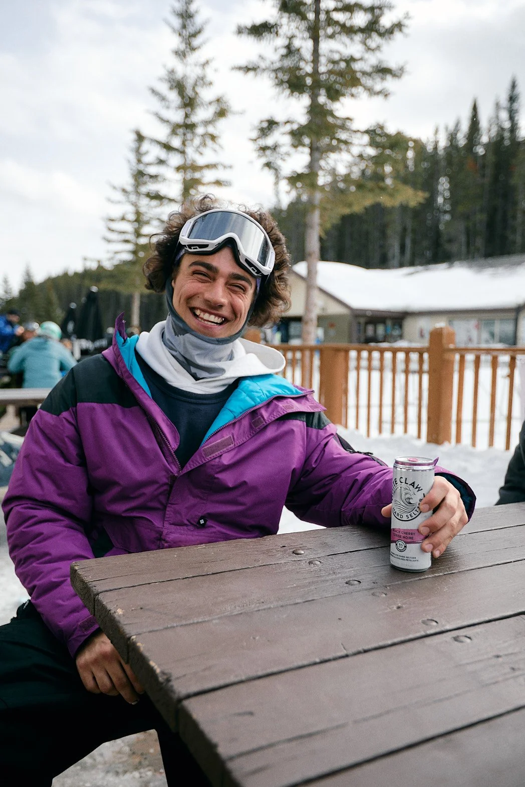 Advertising photographer London campaign image of White Claw Hard Seltzer of skier smiling, wearing retro purple ski jacket.