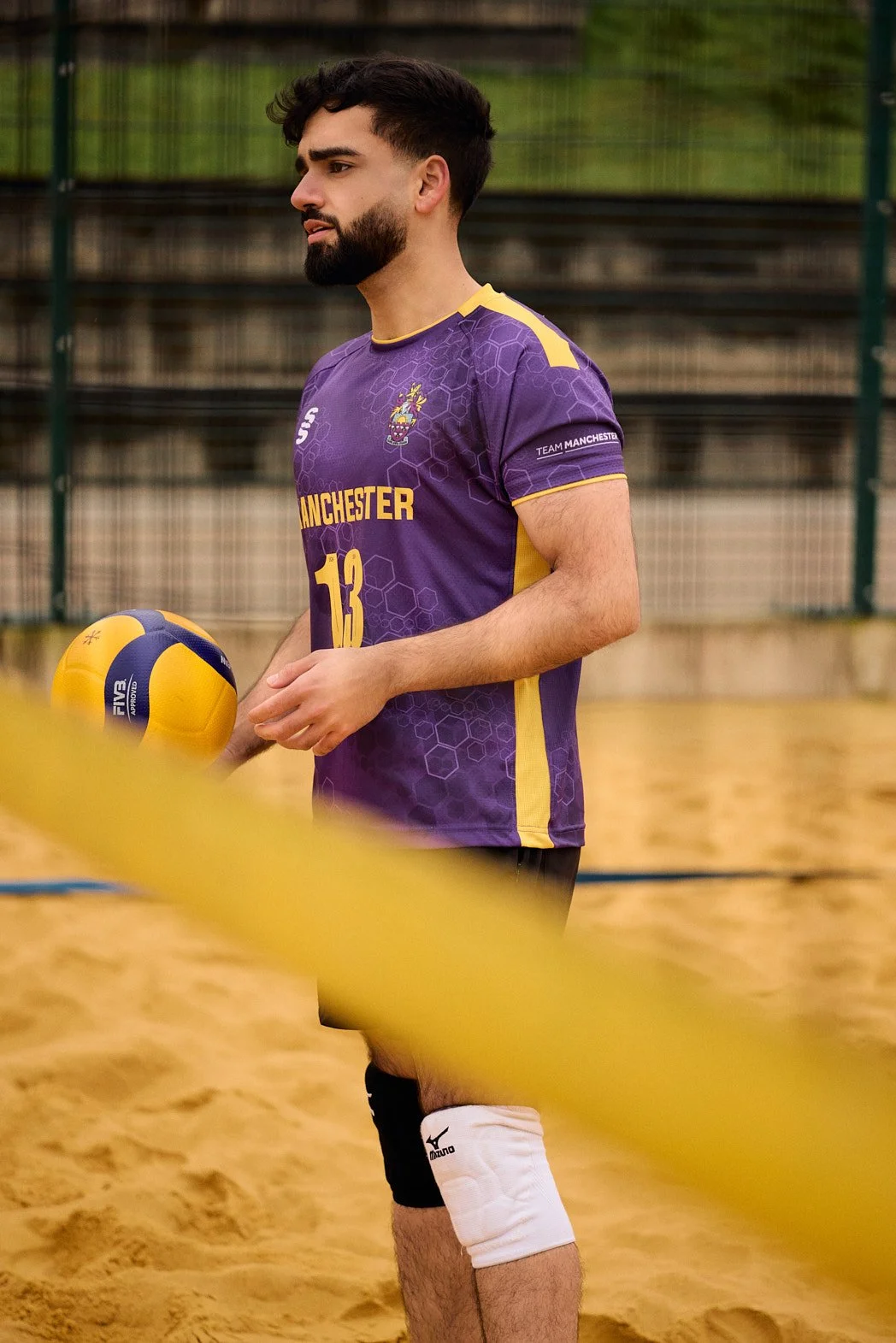 Dating profile photography at a beach volleyball court holding ball looking across between serves