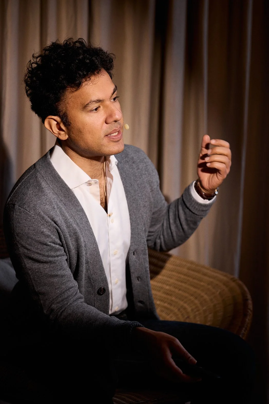 Dating photography portrait in London of man speaking at conference looking off with hand extended out.