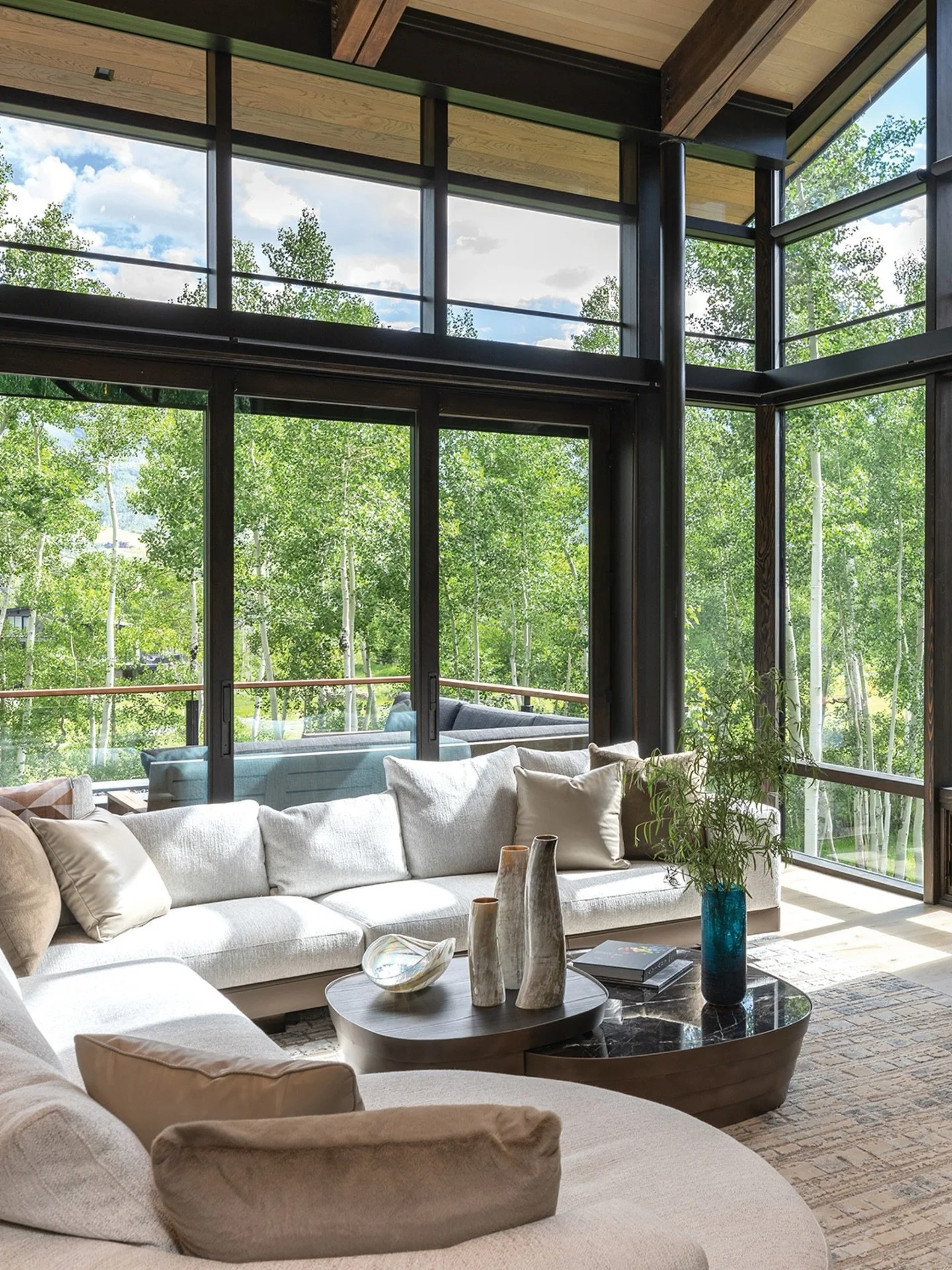Designed for comfort and connection.⁠
⁠
A custom sofa, layered with personal details, sits against a backdrop of expansive glass&mdash;softening the boundary between indoors and the landscape beyond.⁠