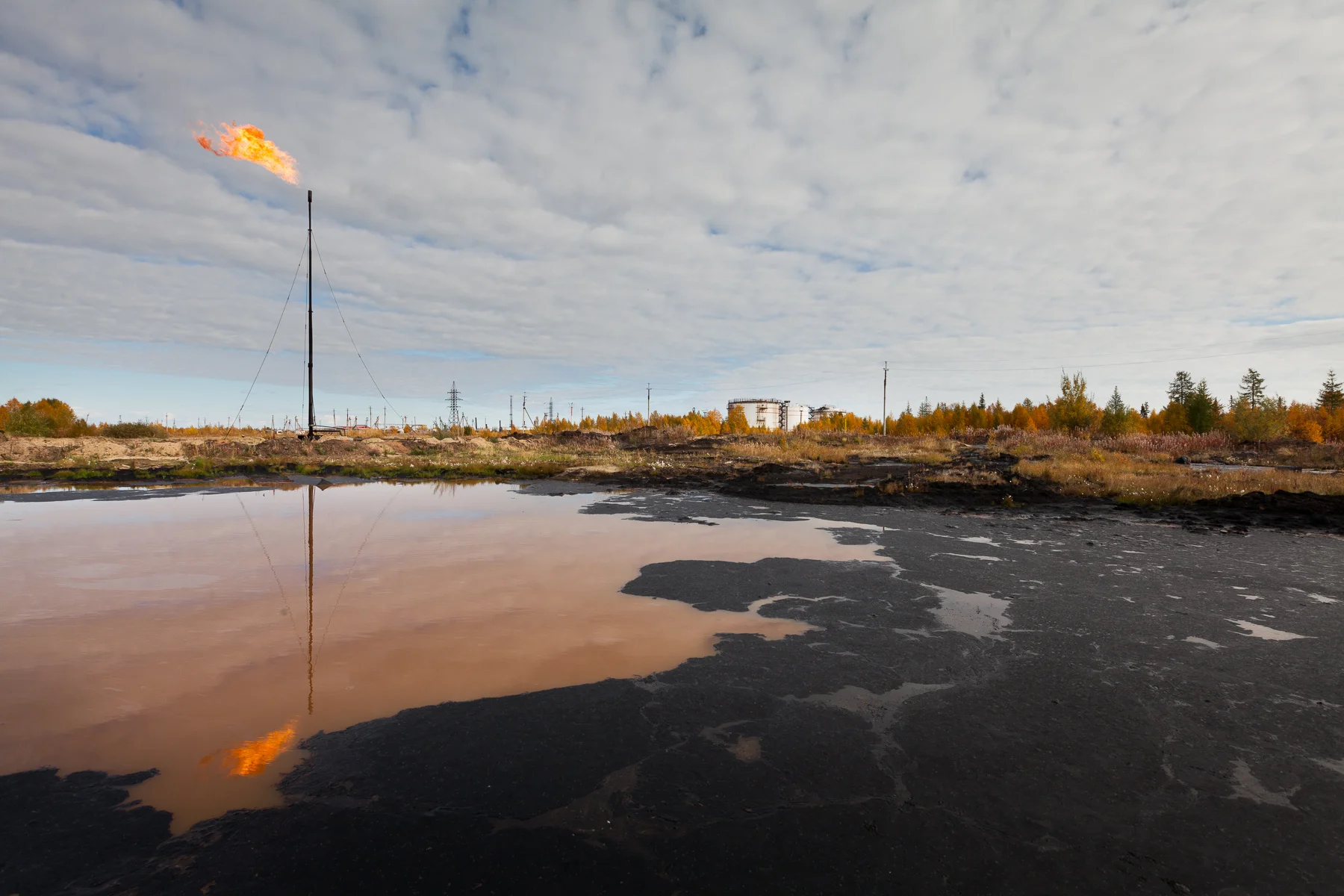 ÖLKATASTROPHE IN RUSSLAND Unzählige Kilometer von Pipelines durchziehen die Republik Komi im Norden Russlands. Viele sind aufgrund des hohen Alters oder durch die stark schwankenden klimatischen Bedingungen marode. Russlands Flüsse transportieren jährlich ca. 500.000 Tonnen Rohöl in den Arktischen Ozean.Die Ölproduktion hat enorme Auswirkungen auf die Natur der Region und ihre Einwohner. Ölseen werden – wenn überhaupt entdeckt – oft nur mit Sand bedeckt. Countless kilometers of pipelines are crossing the Komi Republic in Northern Russia, many of them destroyed by age and climatic conditions. The Russian rivers flush around 500.000 tons of oil to the Arctic ocean every year. The oil industry has tremendous impacts on the region’s nature and inhabitants. Oil spills, if ever detected, are superficially covered with sand.