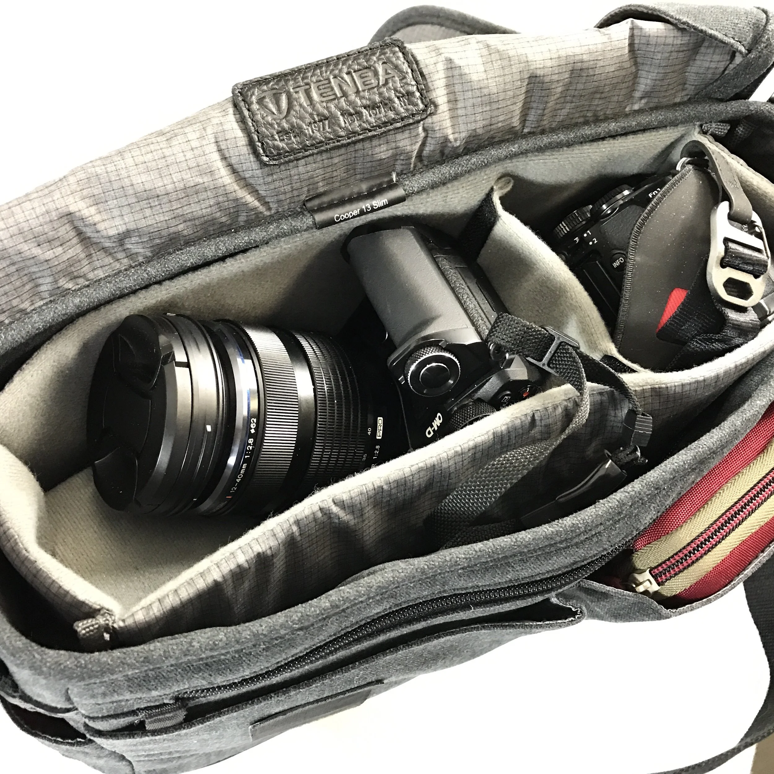 Showing how 12-40mm lens mounted on my E-M5 II rests nicely on soft divider that is on top of the TG Tracker and 12-32mm lens. Note red Case Logic bag in front expandable pocket.
