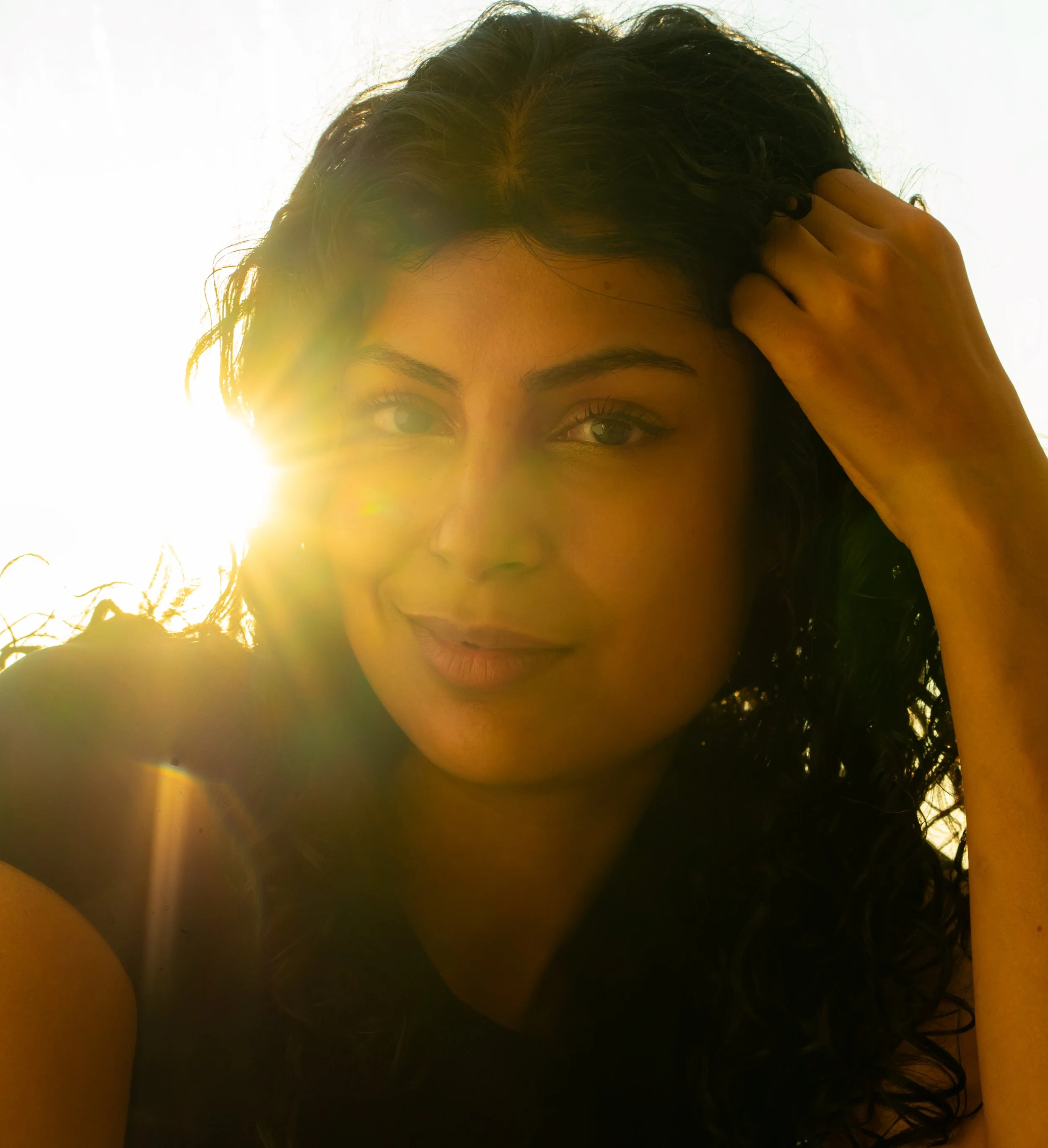 Close up portrait of a beautiful Pakistani woman smiling. Lens flare covering her features just a bit. Location: Vanity Fair , NYC