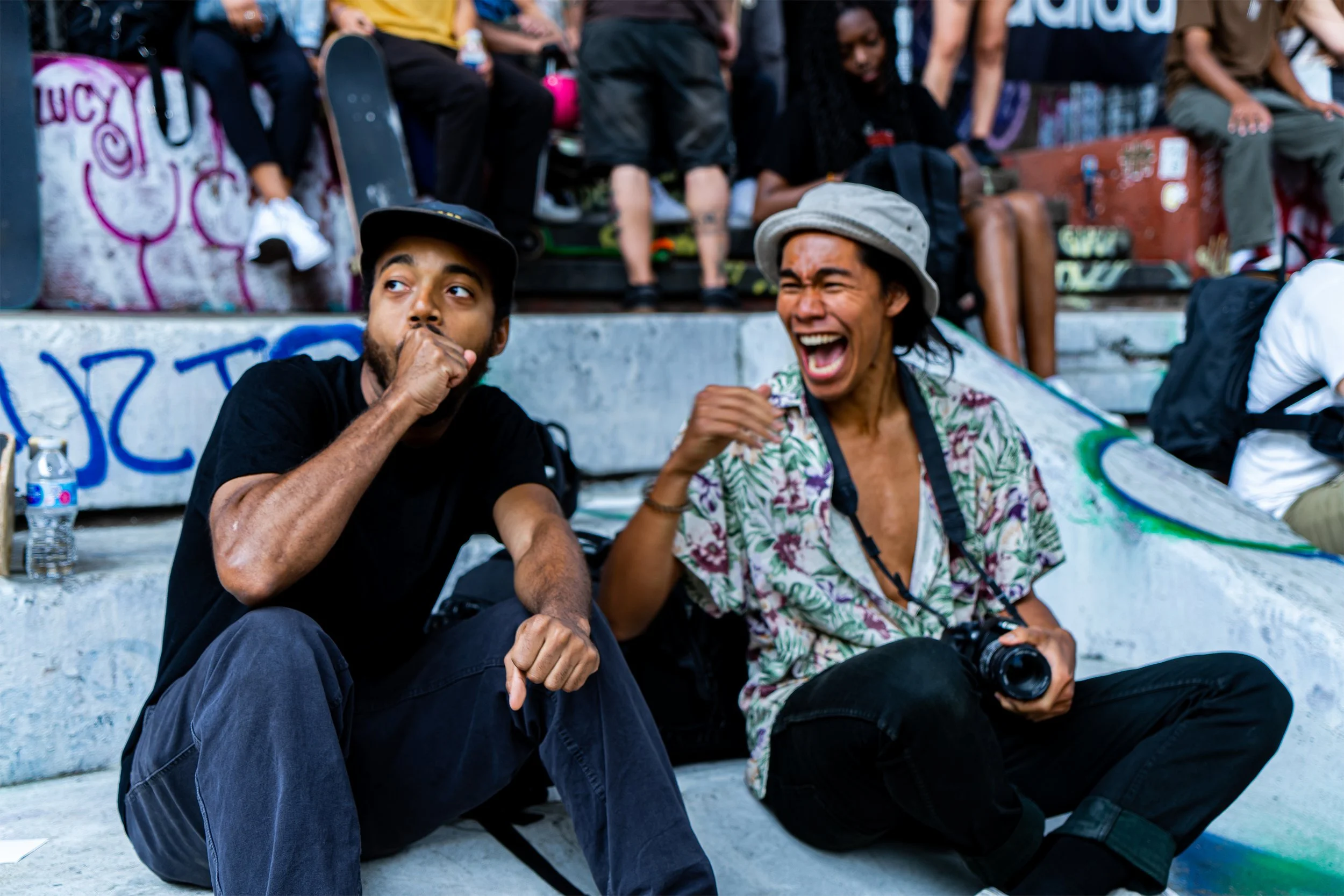 Two photographers at the skatepark laughing at the action. LES Skatepark, NYC. Natural lighting. Shot on Sony A7II