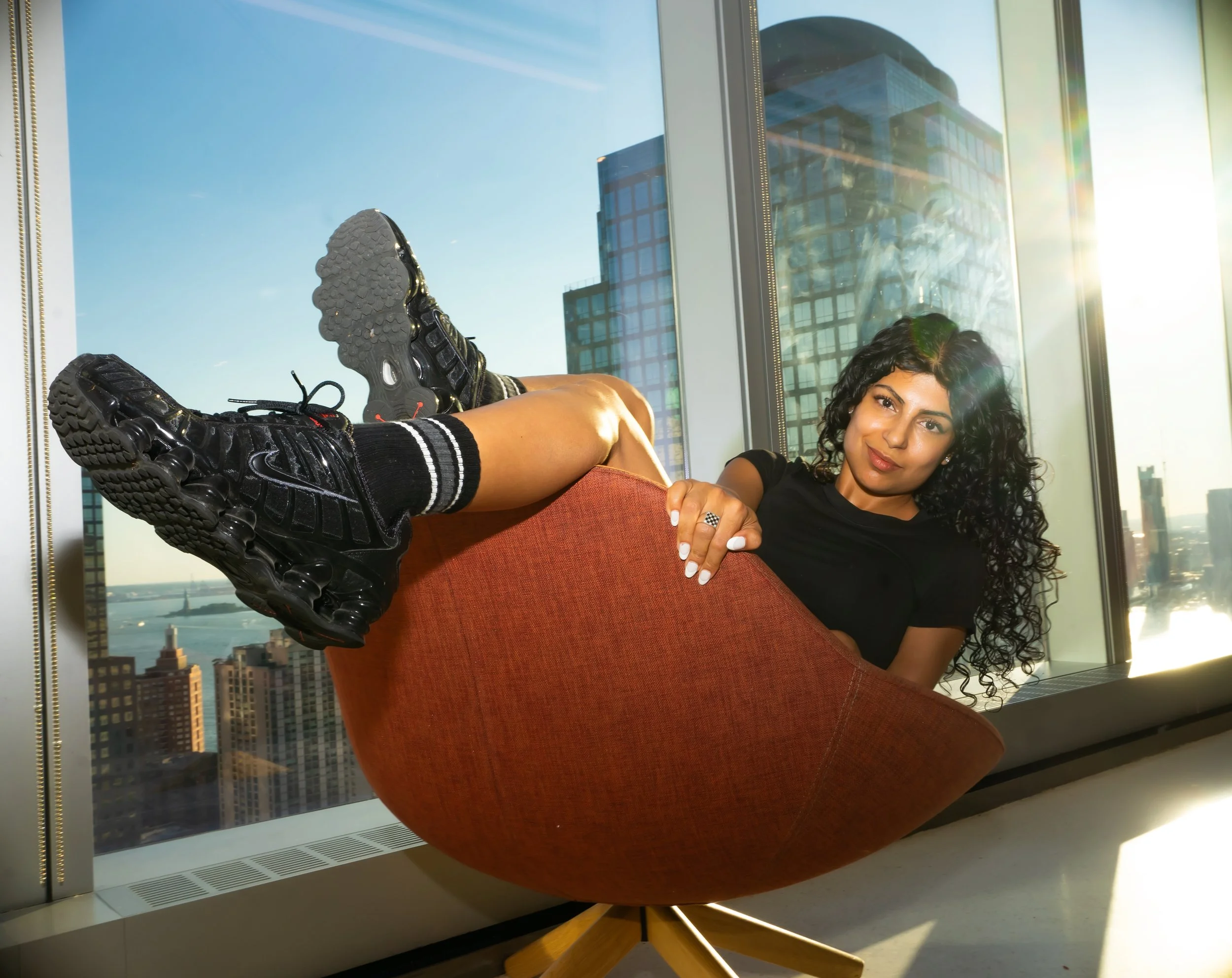 Portrait of a woman in an office chair with her feet kicked up. Editorial, natural light + flash. Location: Vanity Fair , NYC