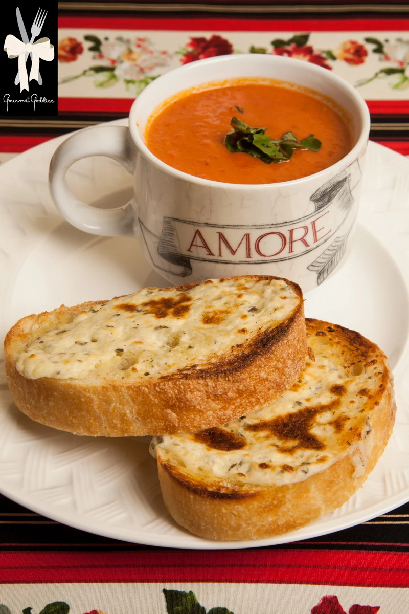 Italian Tomato Soup with Garlic and Herb Cheese Crostini – now that’s amore!
Oh baby it’s cold outside so here’s a recipe from The Gourmet Goddess that will warm and delight you.
During the winter, our thoughts turn to those things that keep us warm. Of course there are blankets and warm woolen mittens to ward off the chill, and if you ask the goddess, it is not an accident we celebrate love on Valentine’s Day during one of the coldest months.
Then, of course, there are comfort foods which we turn to when the temperatures dip below freezing.
The Gourmet Goddess presents a savory low calorie tomato soup made Italian style that says amore to anyone you make it for.
Ingredients - serves 8 2 tablespoons Olive Oil for Sautéing 2 tablespoons Butter ¾ diced Sweet Onion 1 stalk Celery diced 1 Carrot diced 5 cloves chopped Garlic (plus 3 whole cloves to simmer in pot) 2 - 32oz. cans of Italian Tomatoes ¼ cup Red Wine 1 can (½ cup) Tomato Paste 1 tablespoon sugar 1 teaspoon Dried Oregano 1 teaspoon Salt ½ teaspoon Pepper ¾ cup Heavy Cream 1 cup of Fresh Basil Parmesan Shavings for garnish
Directions Sauté onion, carrot and celery for 10 – 12 minutes. Add chopped garlic and sauté 2 minutes. Puree vegetables with tomatoes and return to pot. Add wine, tomato paste and seasonings and simmer for an hour. Turn off and add cream to pot. Stir well.
Garlic Herb Crostini Loaf of Olive Oil Ciabatta sprinkled with Sea Salt 6 ounces of soft garlic and herb cheeses ½ cup grated parmesan cheese
Directions
Drizzle of olive oil, extra for brushing bread. Line a cookie sheet with parchment paper. Slice ciabatta in half inch slices. Brush bread with olive oil. Mix cheese and olive oil and spread on bread. Broil for 1 minute monitoring carefully. Serve crostini floating on top of a bowl of soup OR garnish a cup of soup with a chiffonade of fresh basil and parmesan shavings, crostini on the side.
- Barbara Esatto