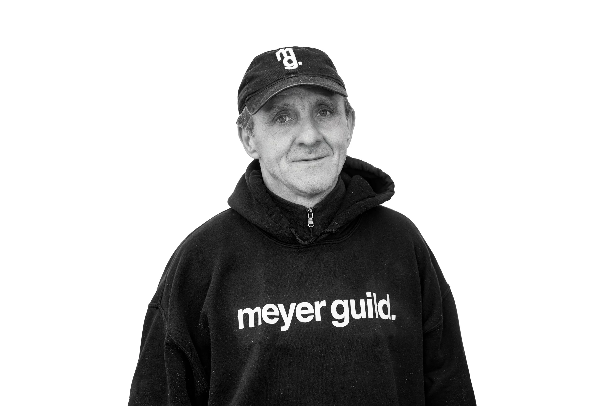 Black and white photo of a man wearing a cap and hoodie with the words "meyer guild."