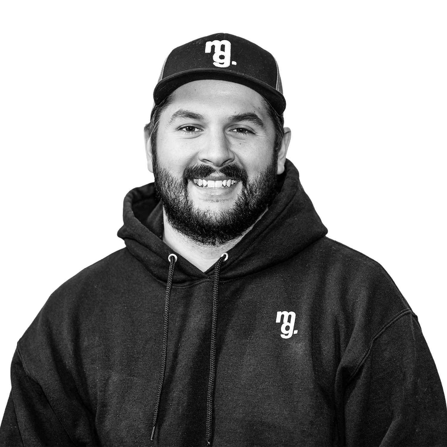 Black and white portrait of a smiling man wearing a hoodie and a baseball cap with the letter 'm' on it.
