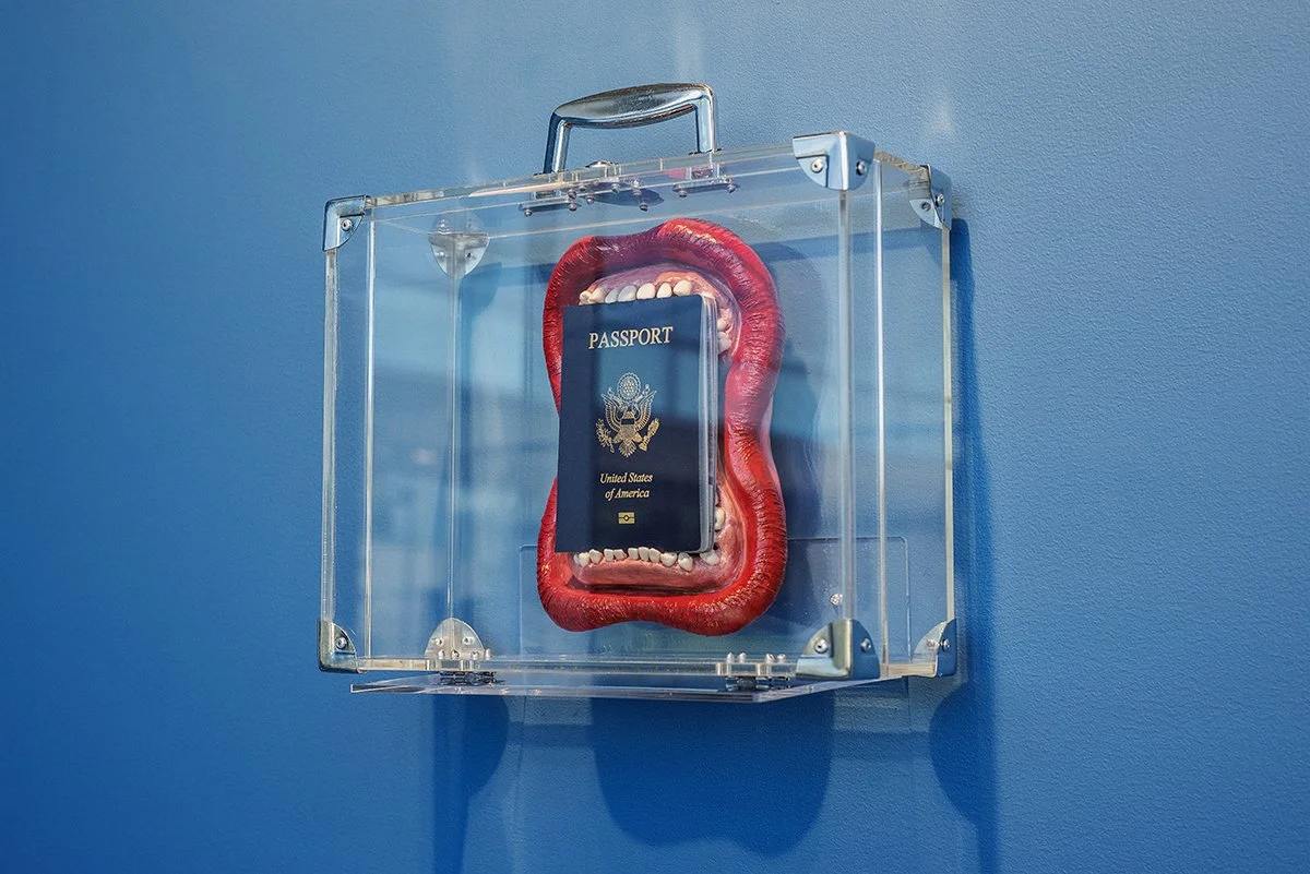   Devouring the Dream  (2025) Intel Lastierre Air dry clay, synthetic teeth, U.S. passport prop, and acrylic suitcase size variable 