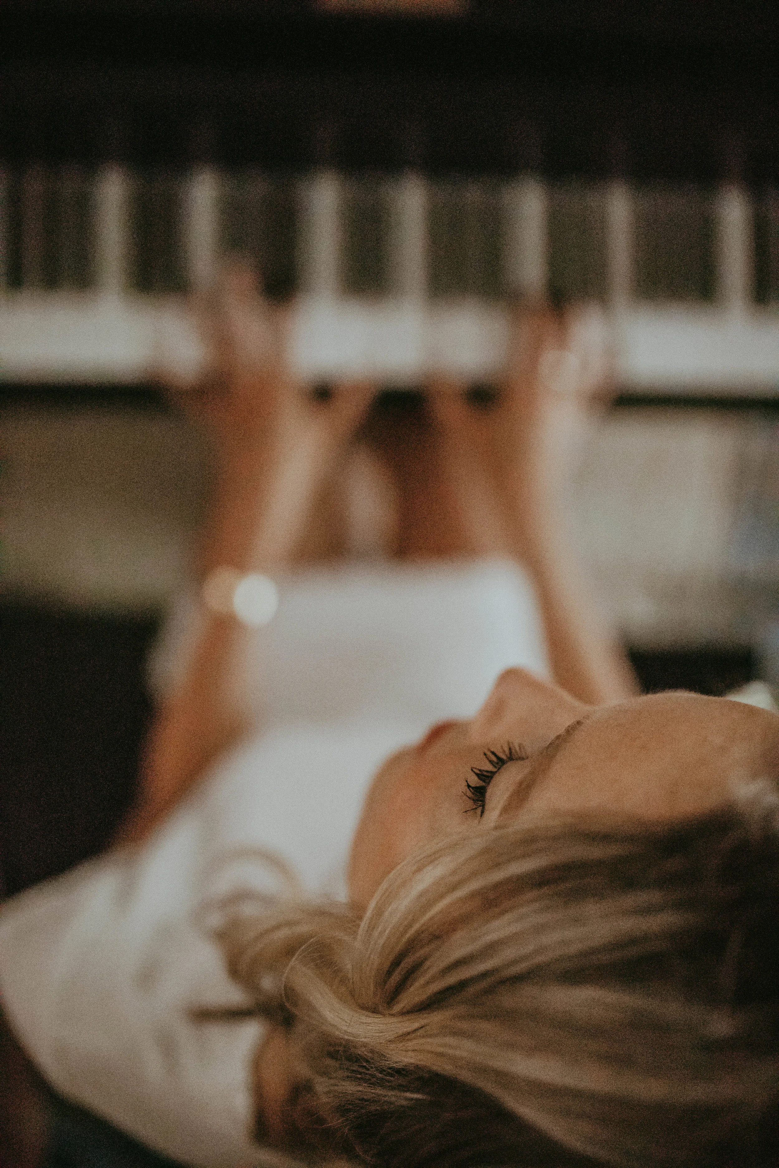 Close-up of a woman lying on a bed near a piano keyboard, focusing on her face and relaxed posture.