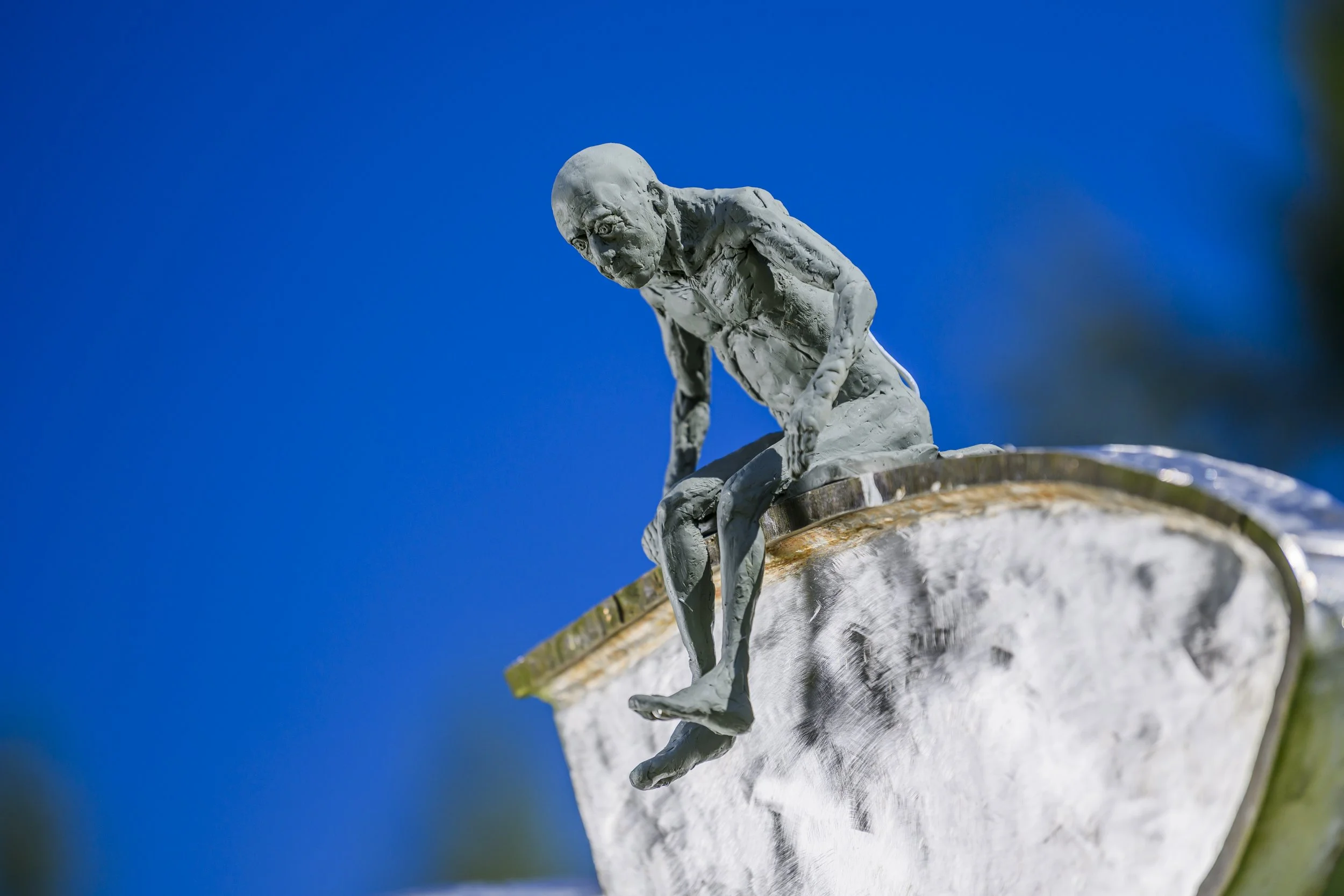 Clay figure interacting with steel sculpture