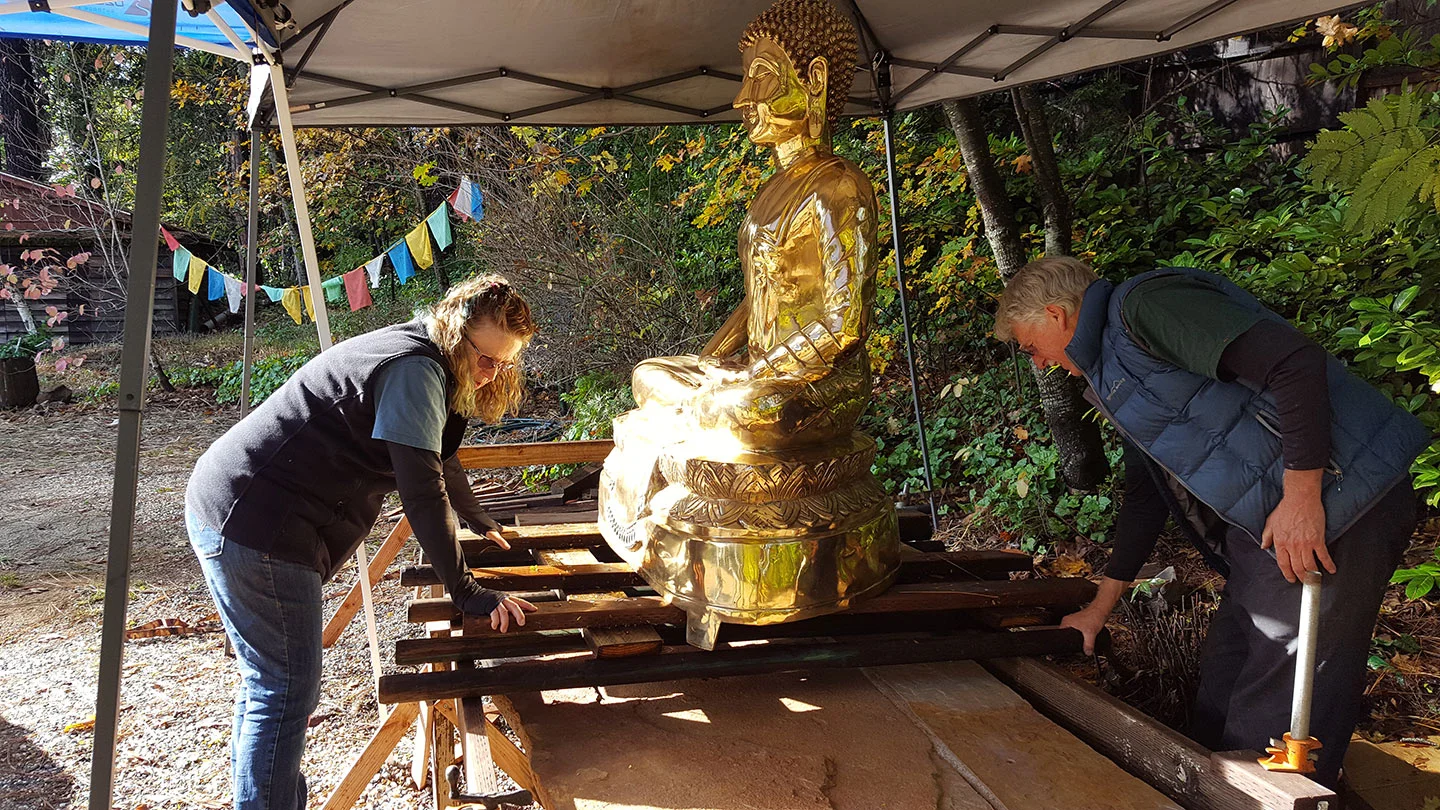 Ann and Rick carefully moving Buddha onto the stone pedestal