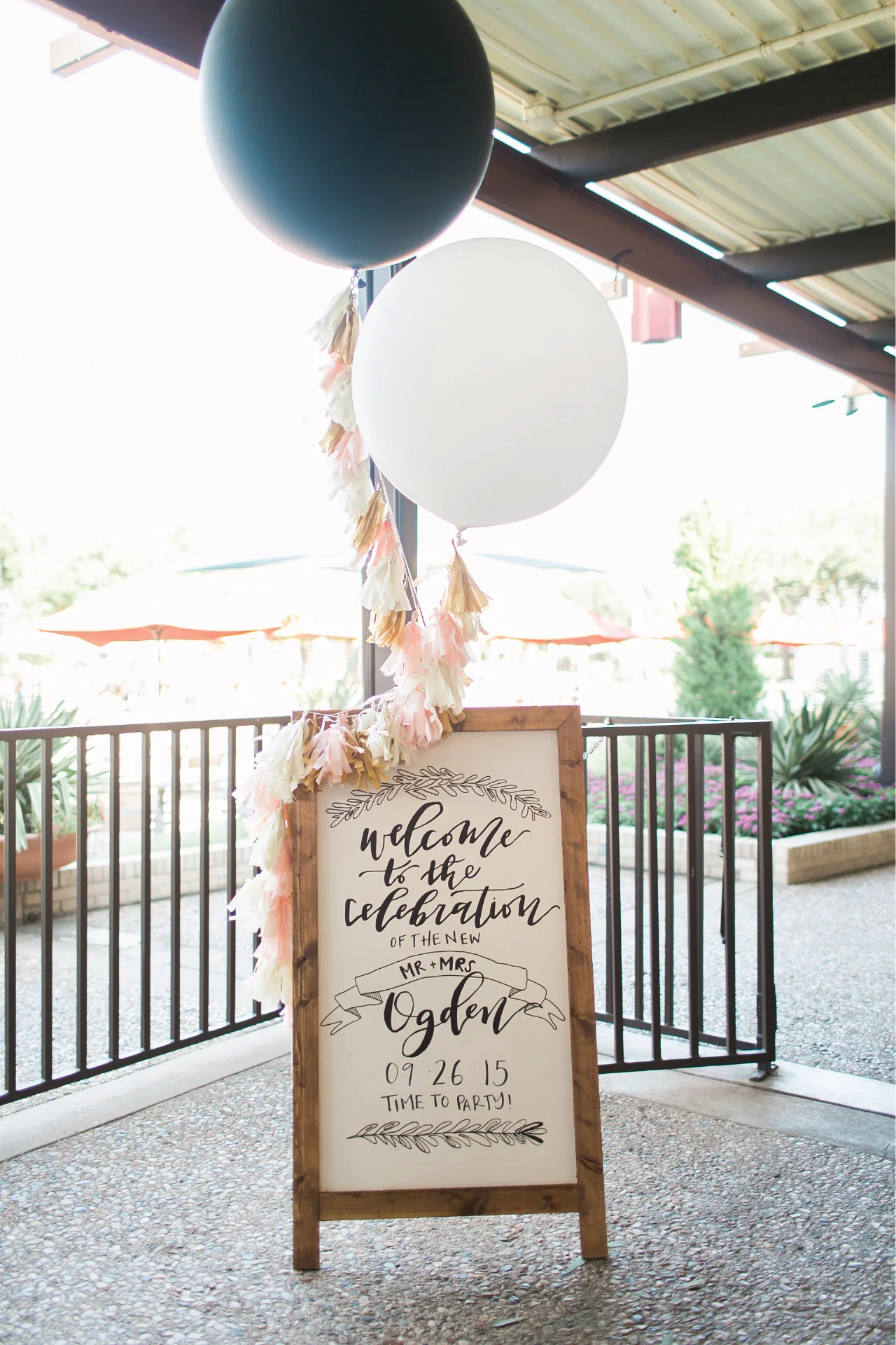 Wedding welcome signage on a handmade wooden easel board, decorated with tassel strings and oversized balloons!