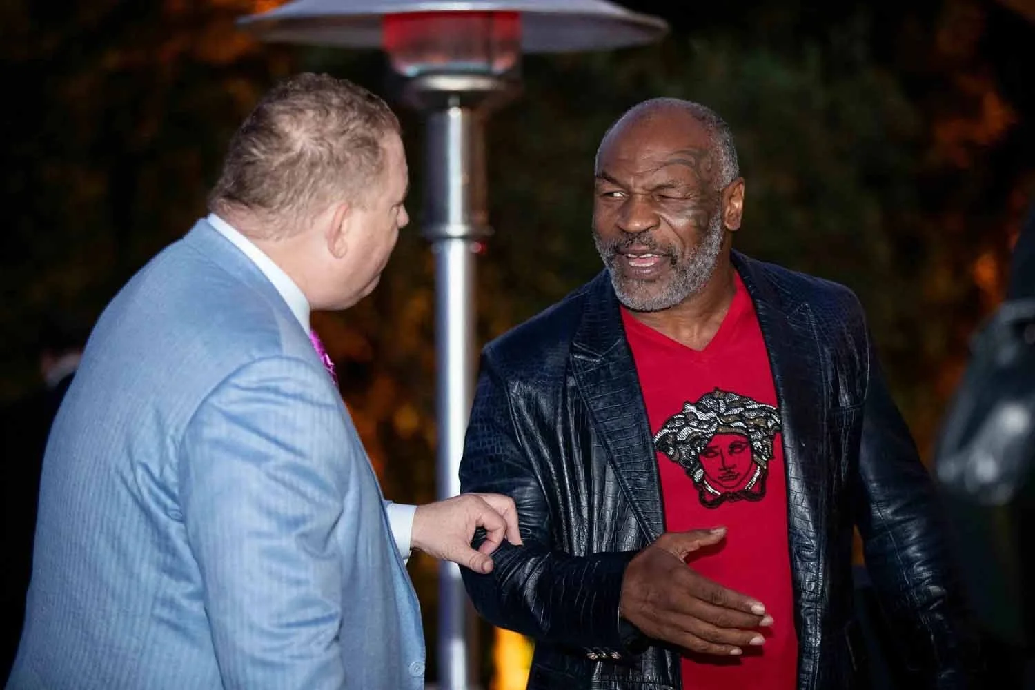 Boxing legend Mike Tyson engaging with a guest at a private networking event at a luxury estate in the Hollywood Hills.
