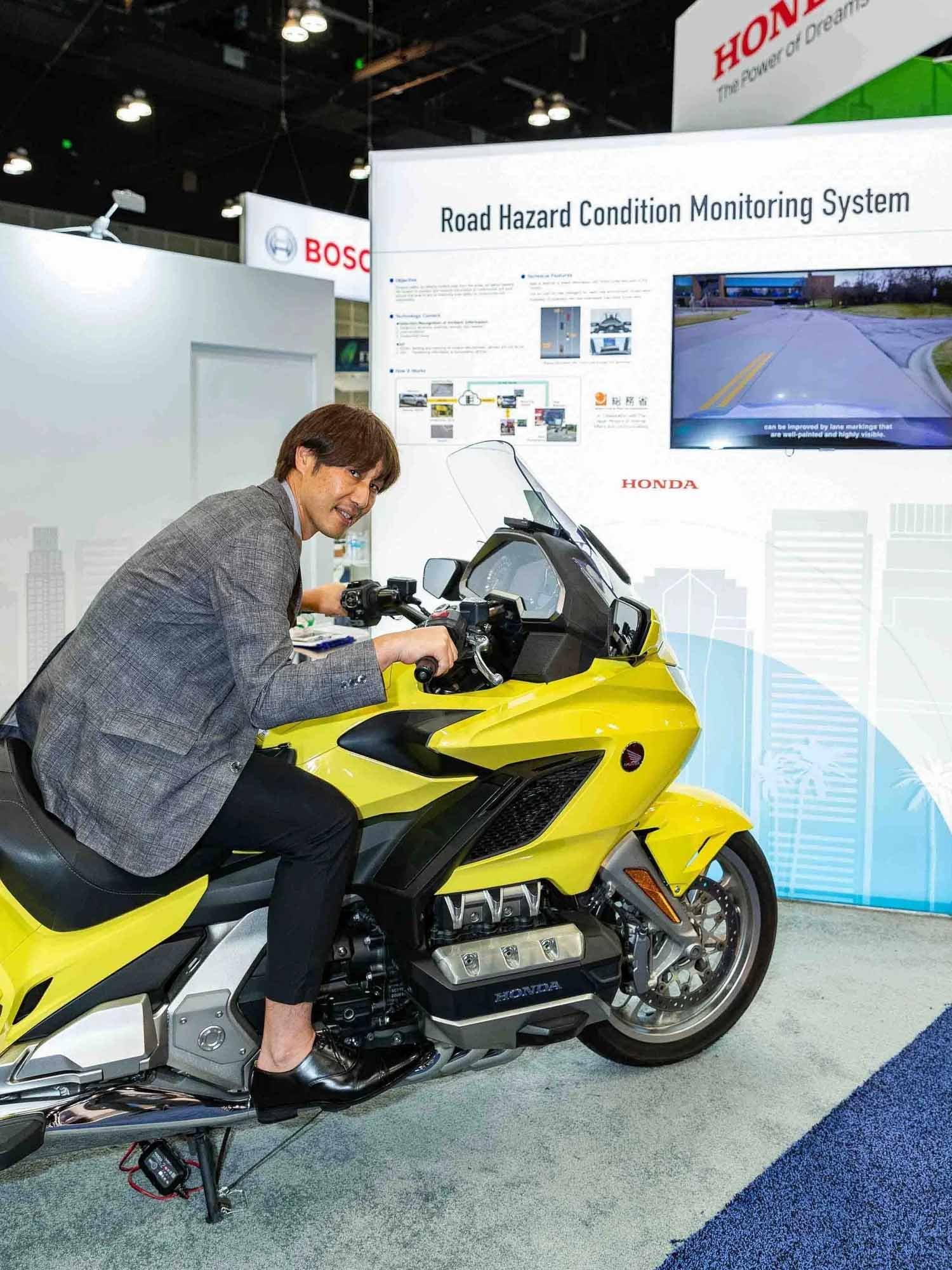 A Honda representative posing with a new Honda motorcycle at a transportation trade show in the Los Angeles Convention Center.