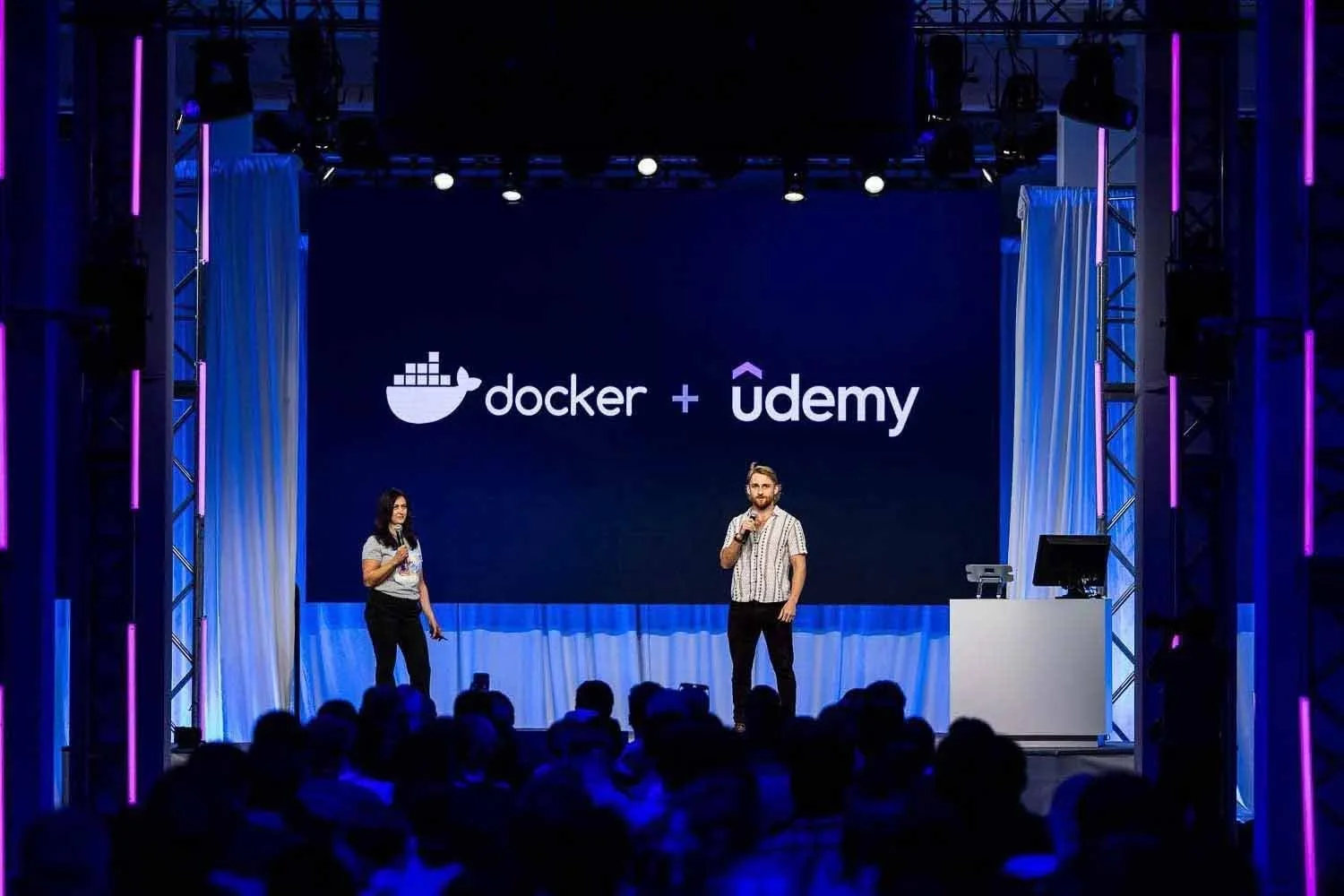 Two keynote speakers discussing the Docker and Udemy developer partnership on stage at the Los Angeles Convention Center.
