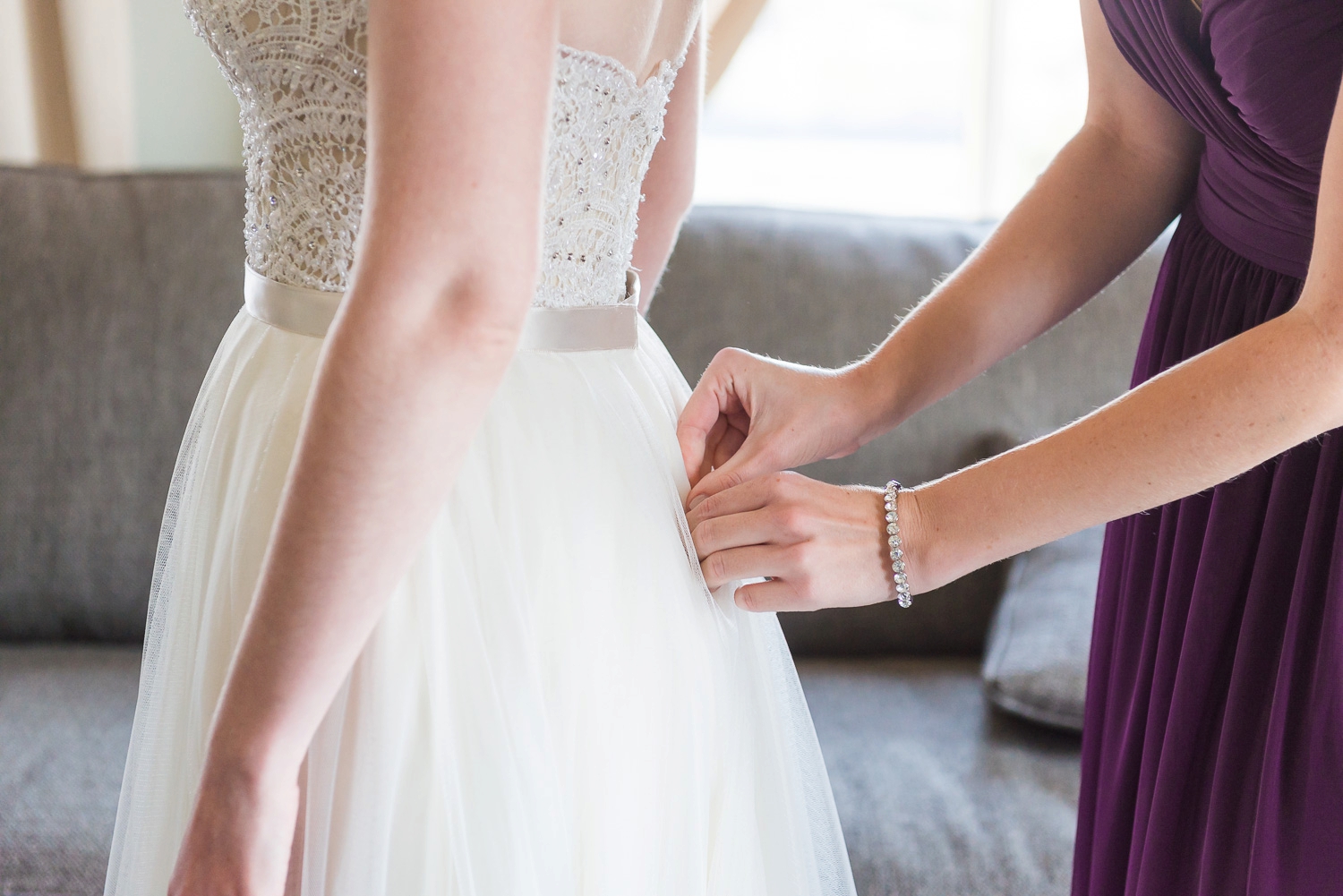 Bridesmaid zipping a bride into her dress