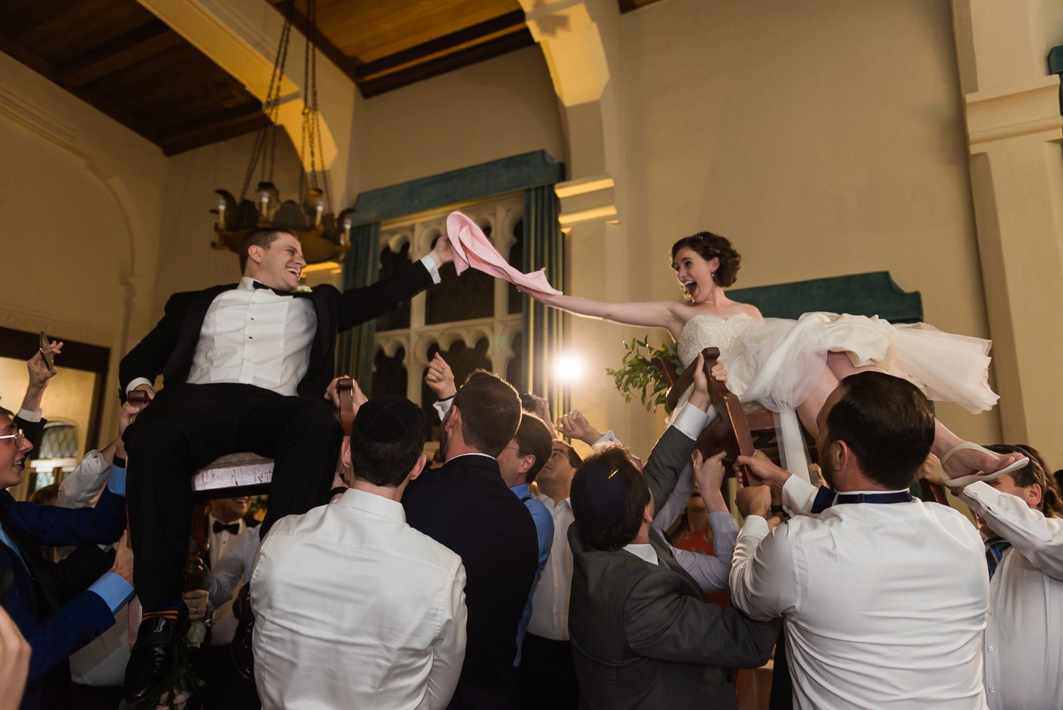 Bride and groom in chairs for the hora dance