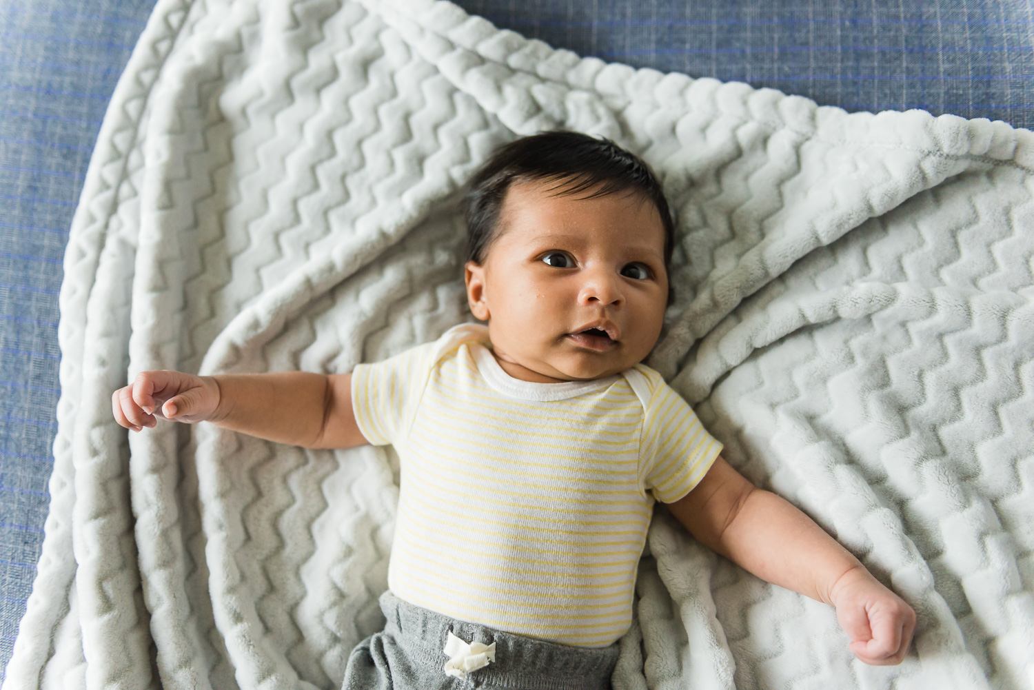 Baby wearing a white t-shirt laying on a blanket