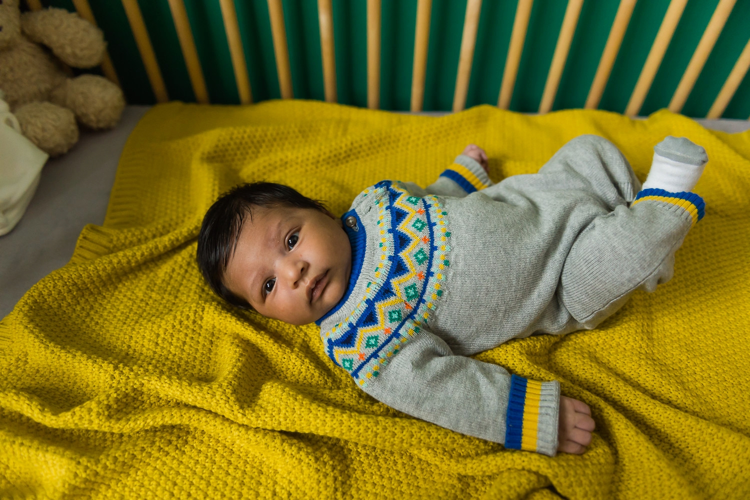 Baby in embroidered onesie laying on a yellow blanket