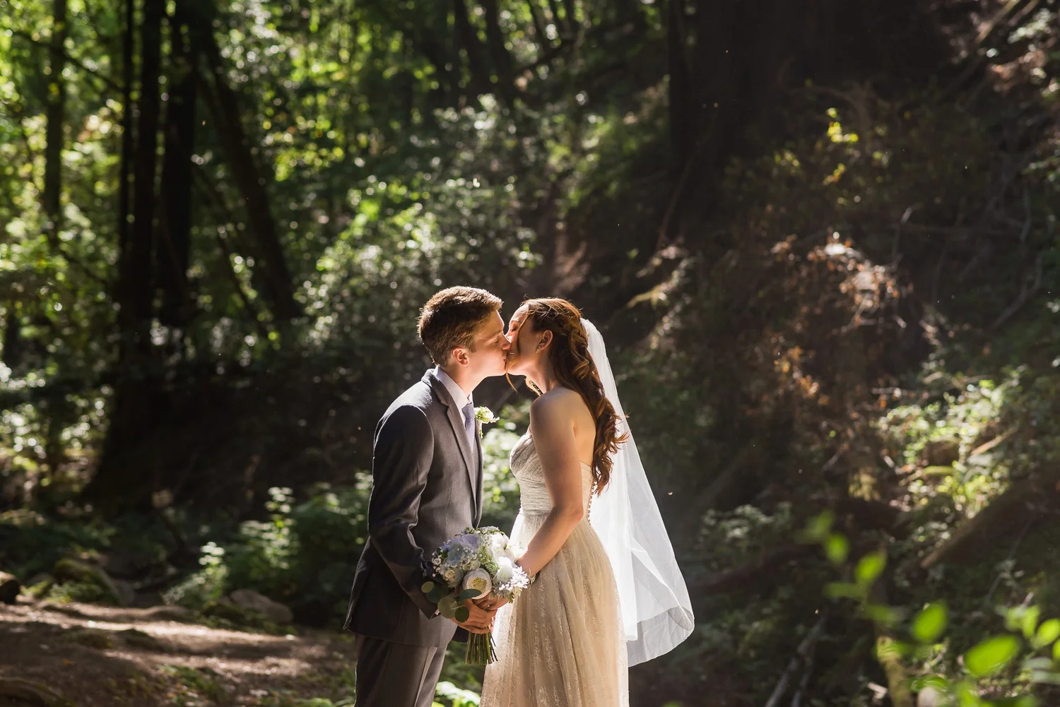 Bride and groom kissing in the woods