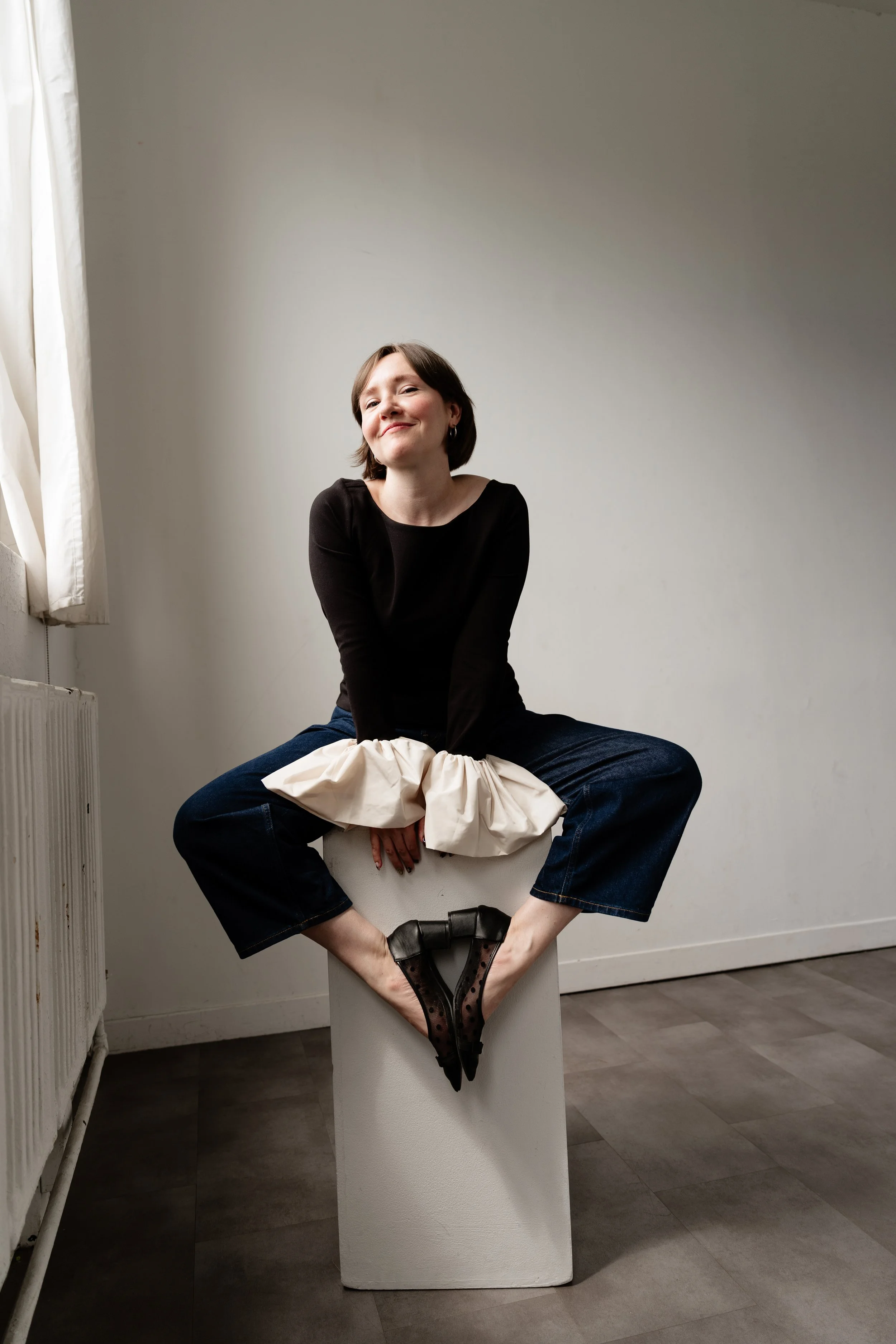 Claren Grosz, a white woman with a short bob, smiles as she poses on a plinth.