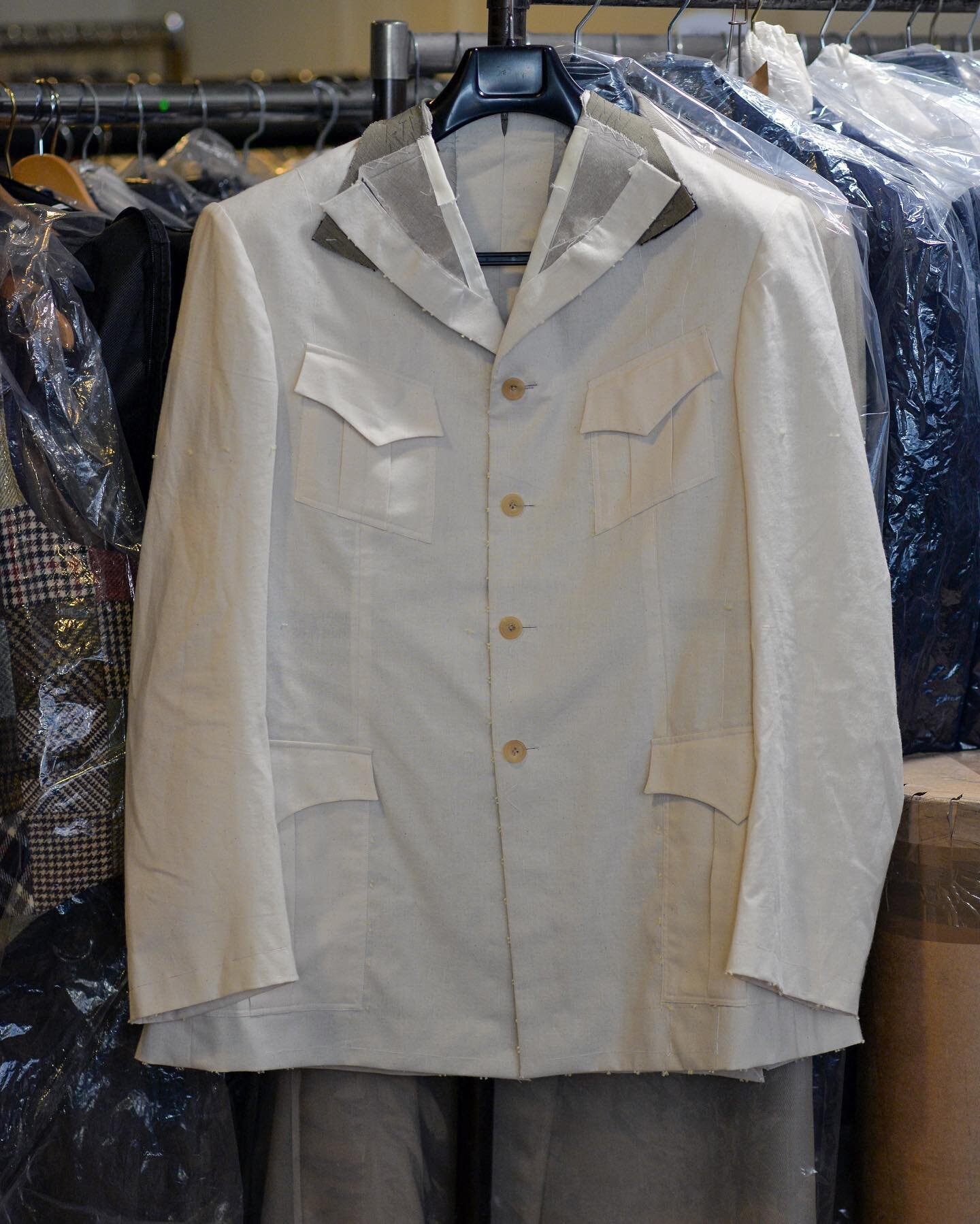A Safari jacket toile hanging in the workshop. 

We make toiles to work on new models, in order to fine tune construction and design before we start into the cloth, in order to move forward for our clients without compromise.
