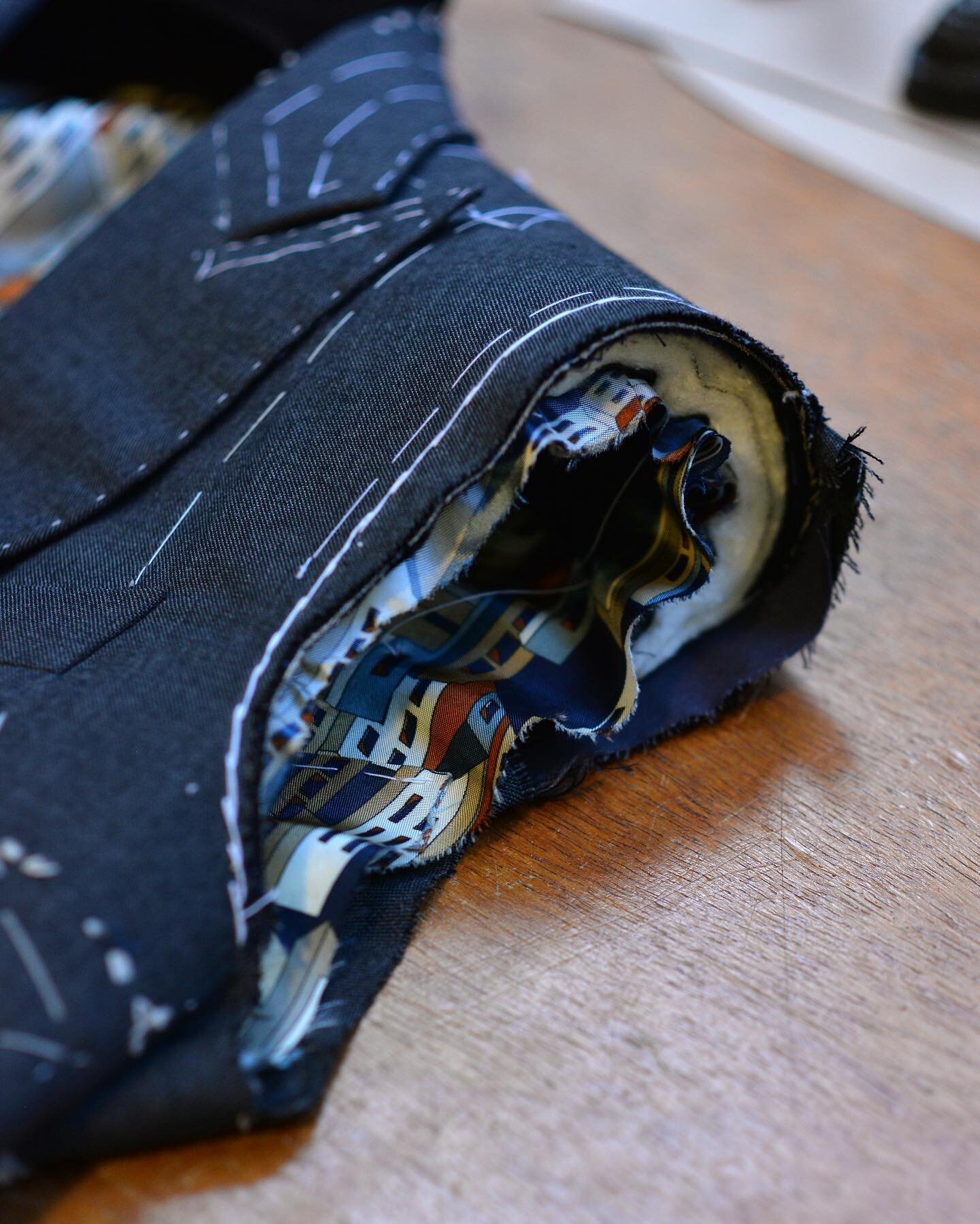 The armhole of our suit jacket, shaped and prepared for the sleeve to be set in and finished . Our handmade shoulder pad and a fancy lining visible within