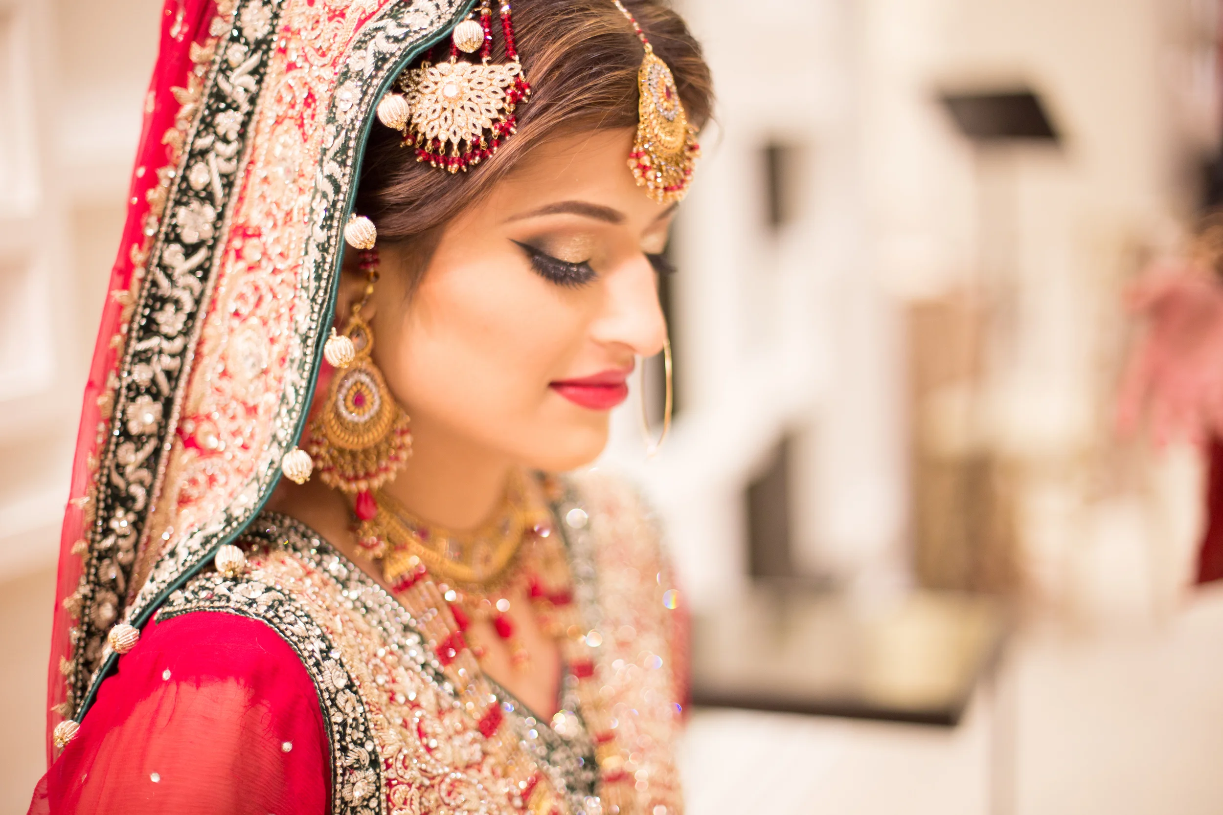 Bride in traditional bridal attire with ornate jewelry and embellished veil.