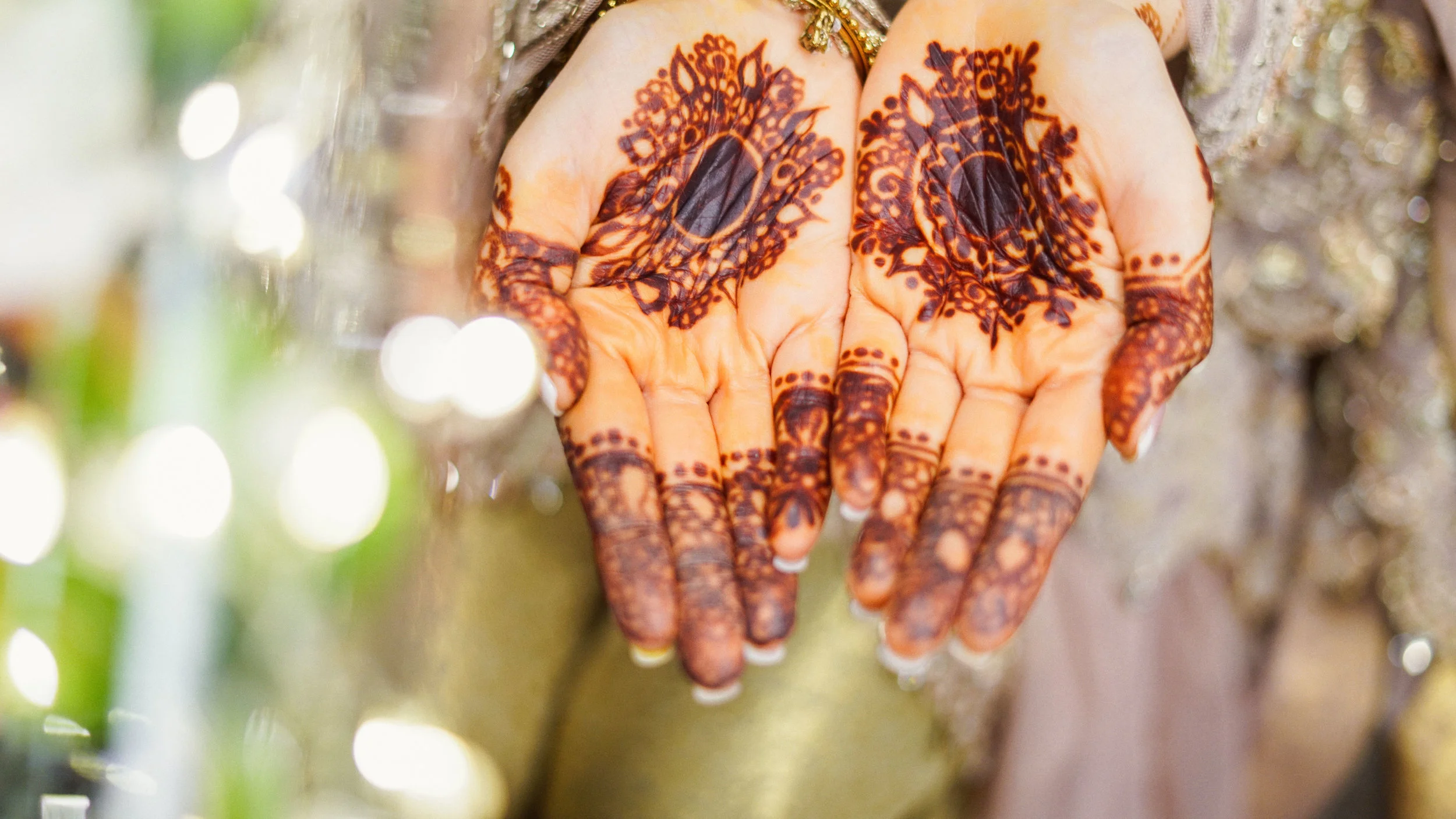 Close-up of hands with intricate henna designs on palms and fingers.