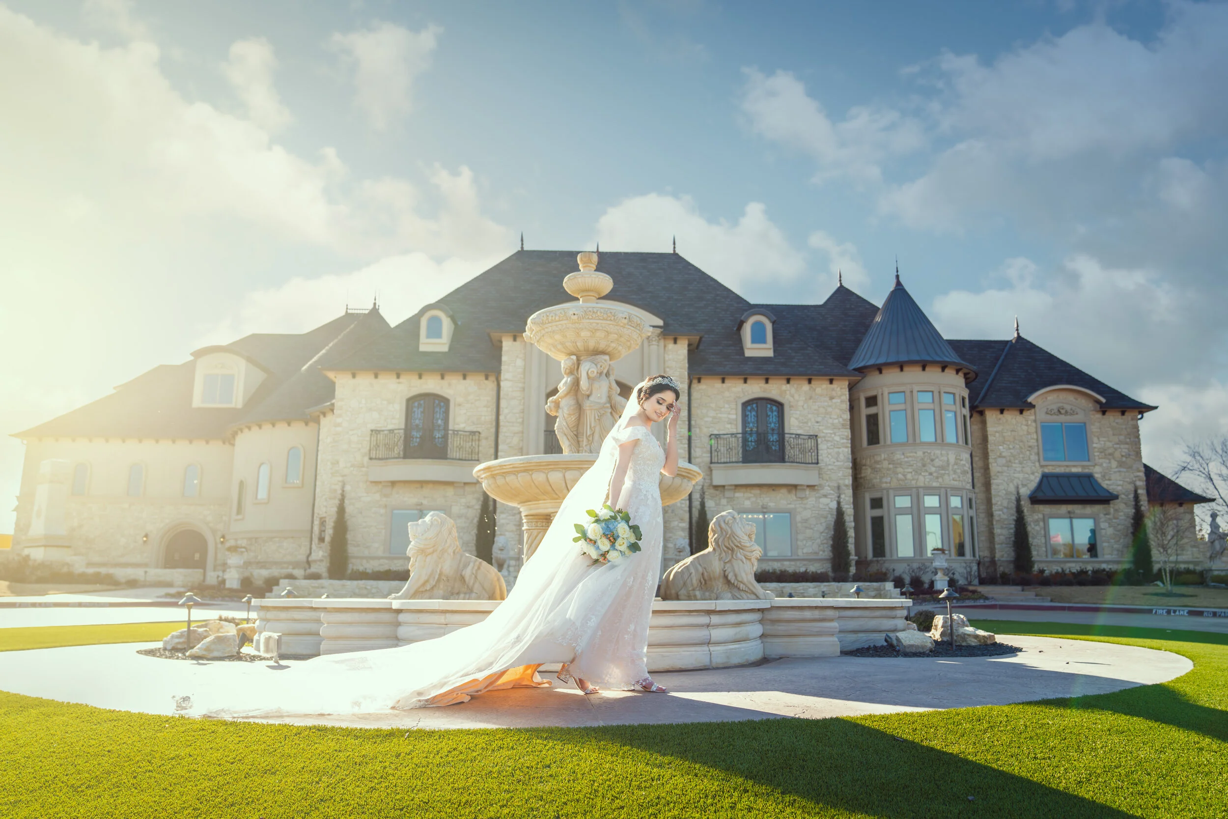 Bride in wedding dress holding bouquet near ornate mansion and fountain