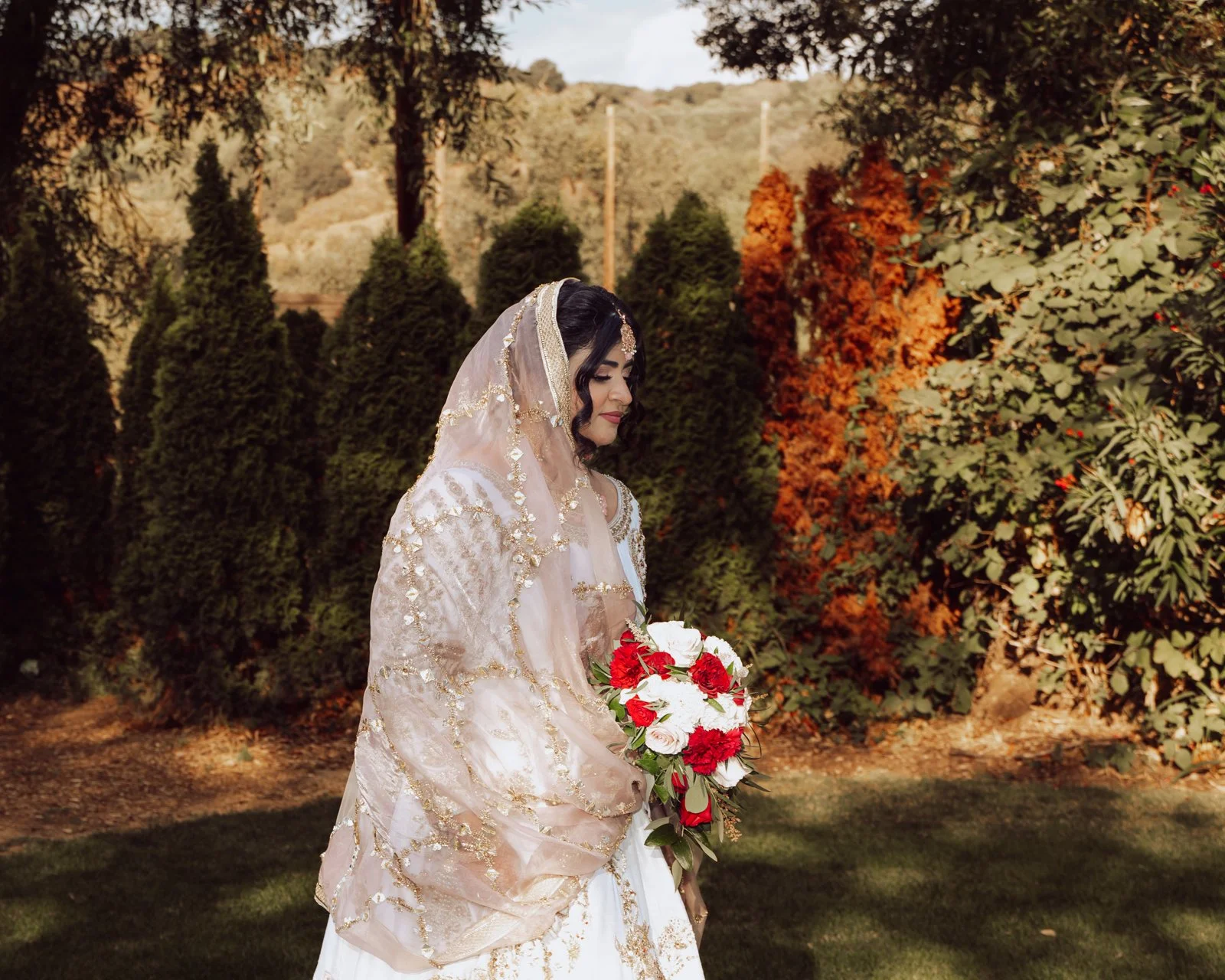 Bride in traditional outfit holding bouquet outdoors