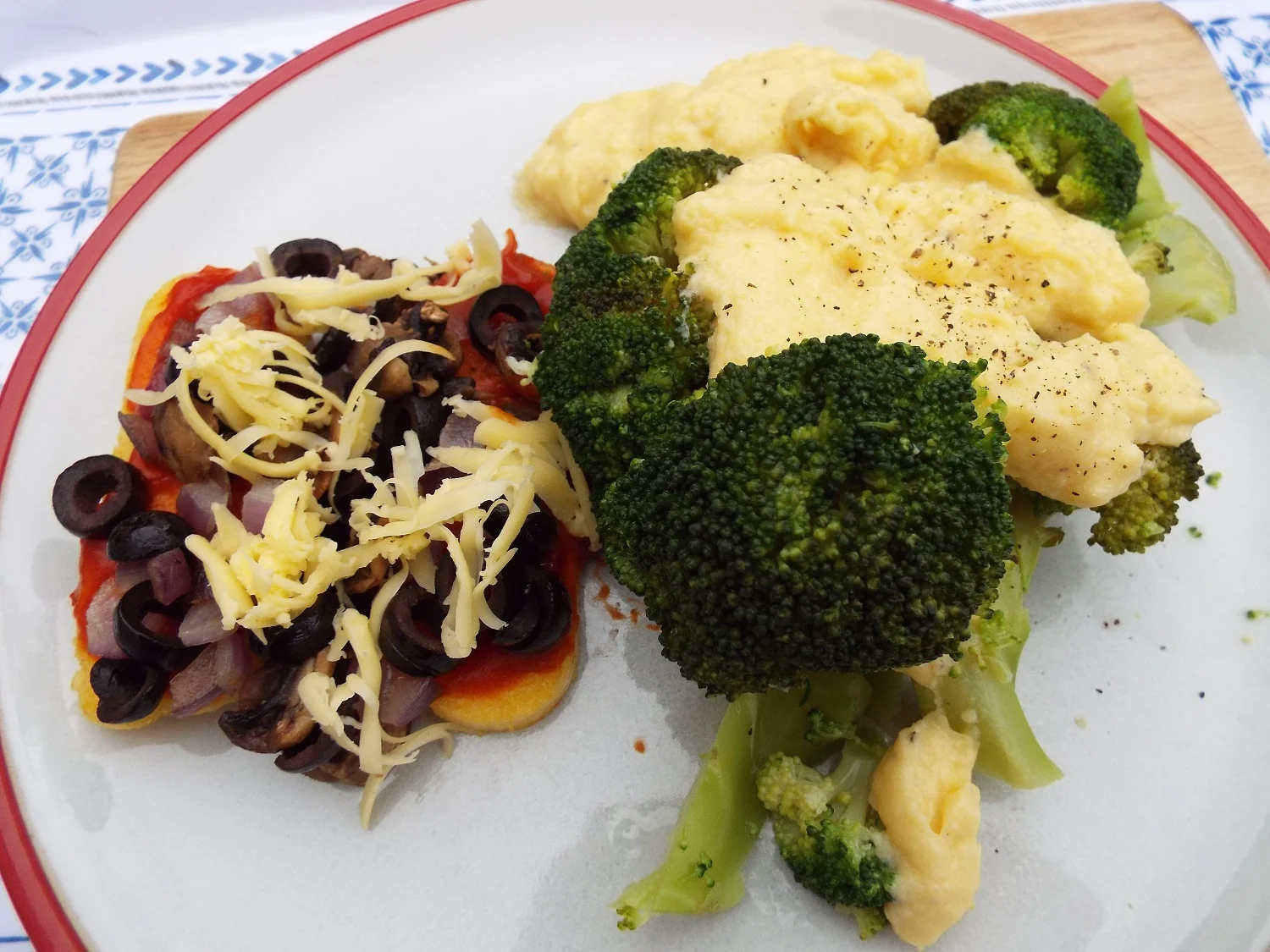 Polenta slices, fried in olive oil, with toppings of tomato, onion, black olives, mushrooms and vegan cheese, with broccoli in cheese sauce