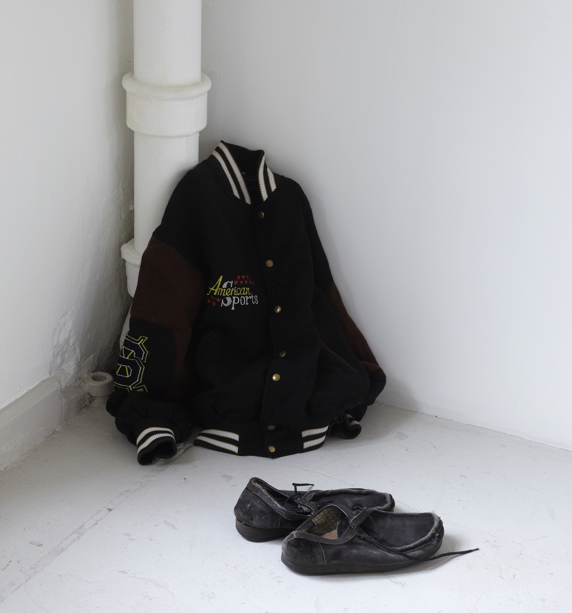  Amel Ibrahimovic  My Refugee Shoes and My Refugee Clothes  (1998) Shoes and jacket placed in a corner, dimensions variable Courtesy the artist 