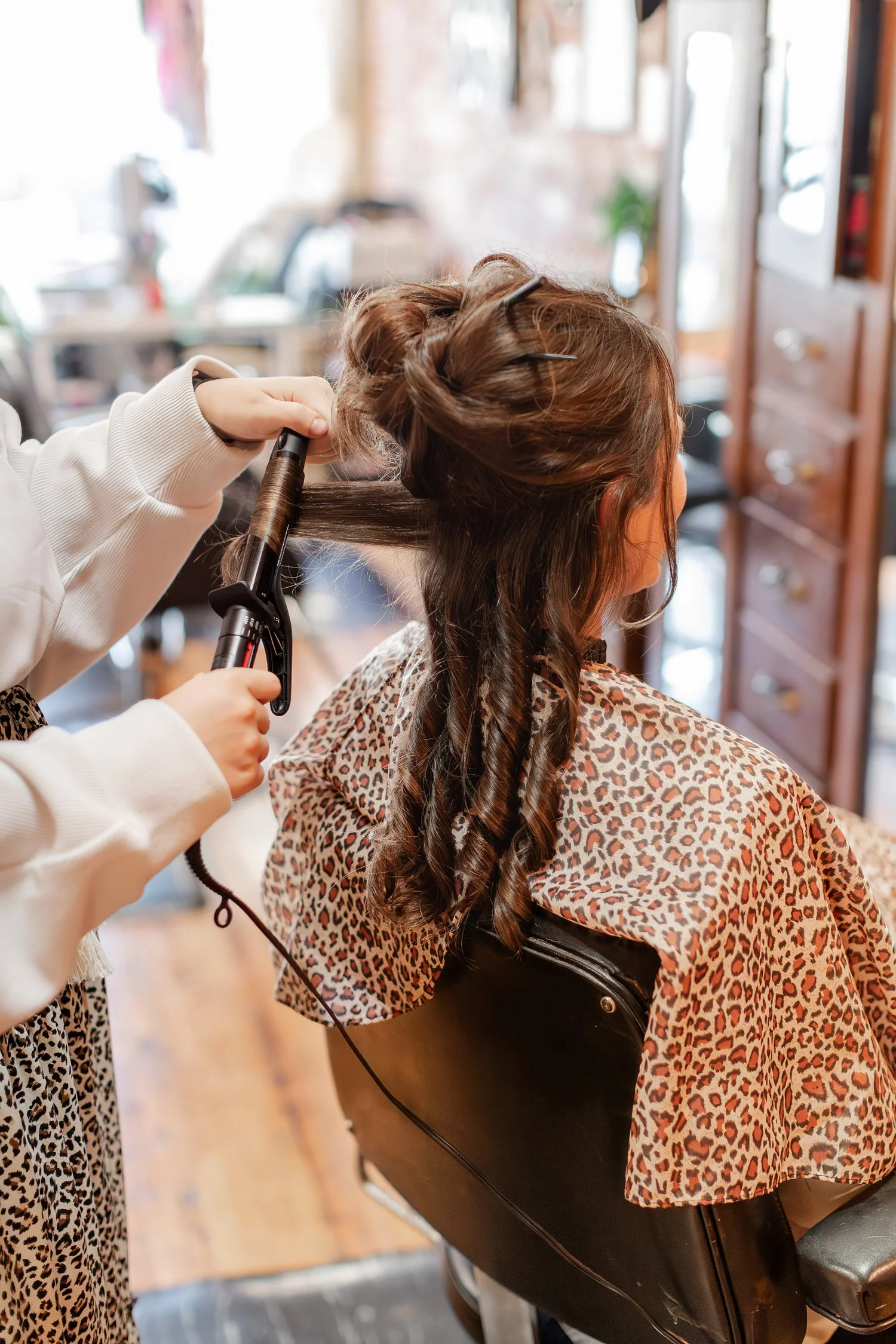 stylist curling a client's hair with a curling iron, seen from behind the chair, Hair, Heart and Soul, brand photography session, Bolivar MO