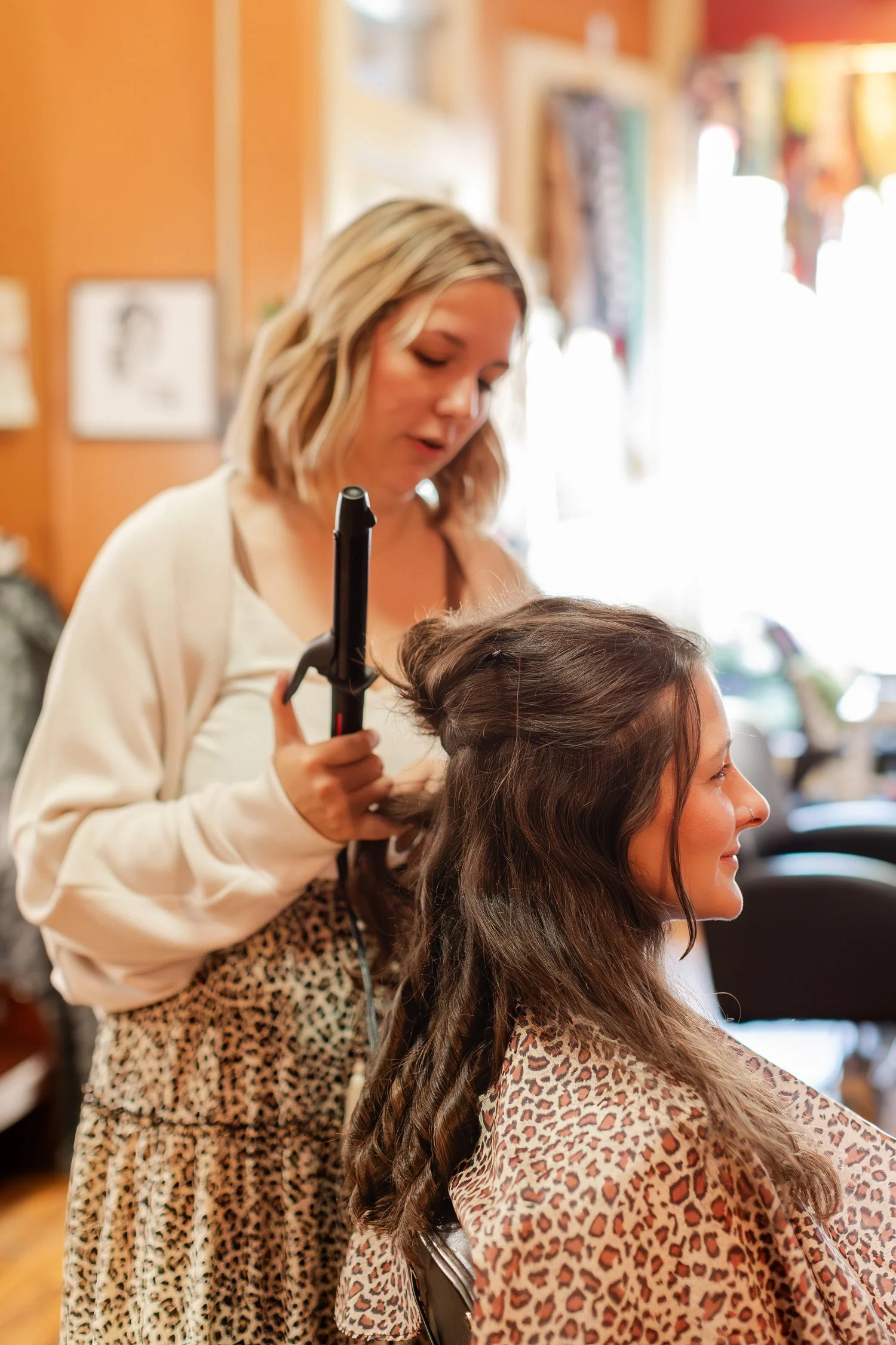 stylist curling the front of a client's hair while she smiles, Hair, Heart and Soul, brand photography session, Bolivar MO