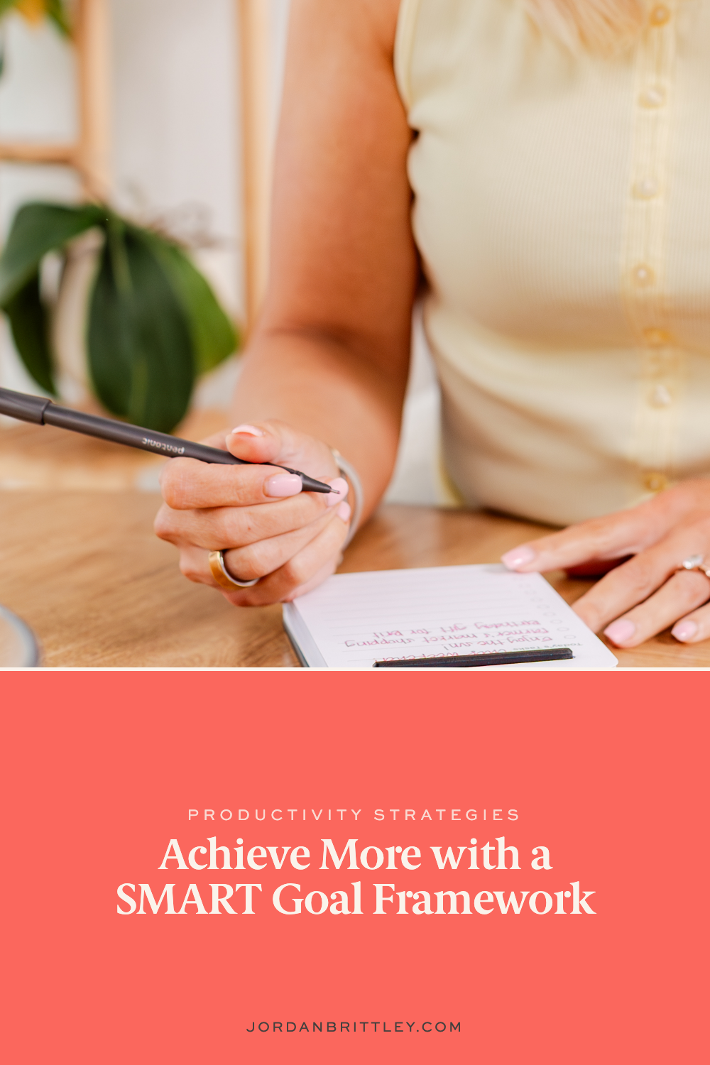 Woman writing business goals in a notebook at a desk.