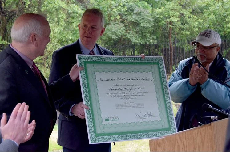 Department of Energy & Environment Director Tommy Wells presents a certificate for Stormwater Retention Credits to the Anacostia Waterfront Trust for its green infrastructure project. 