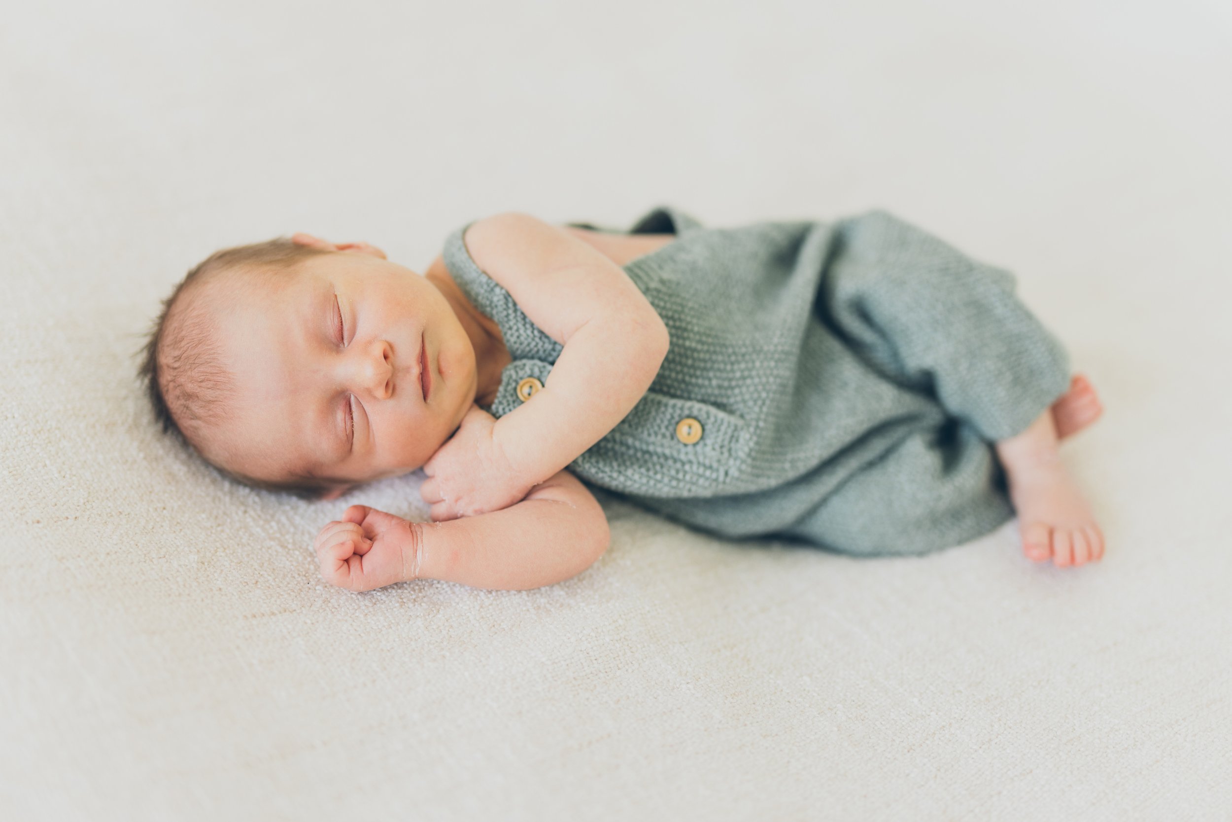  A newborn baby boy wearing a green knitted outfit in RinkaDink Studio Belfast Northern Ireland. 