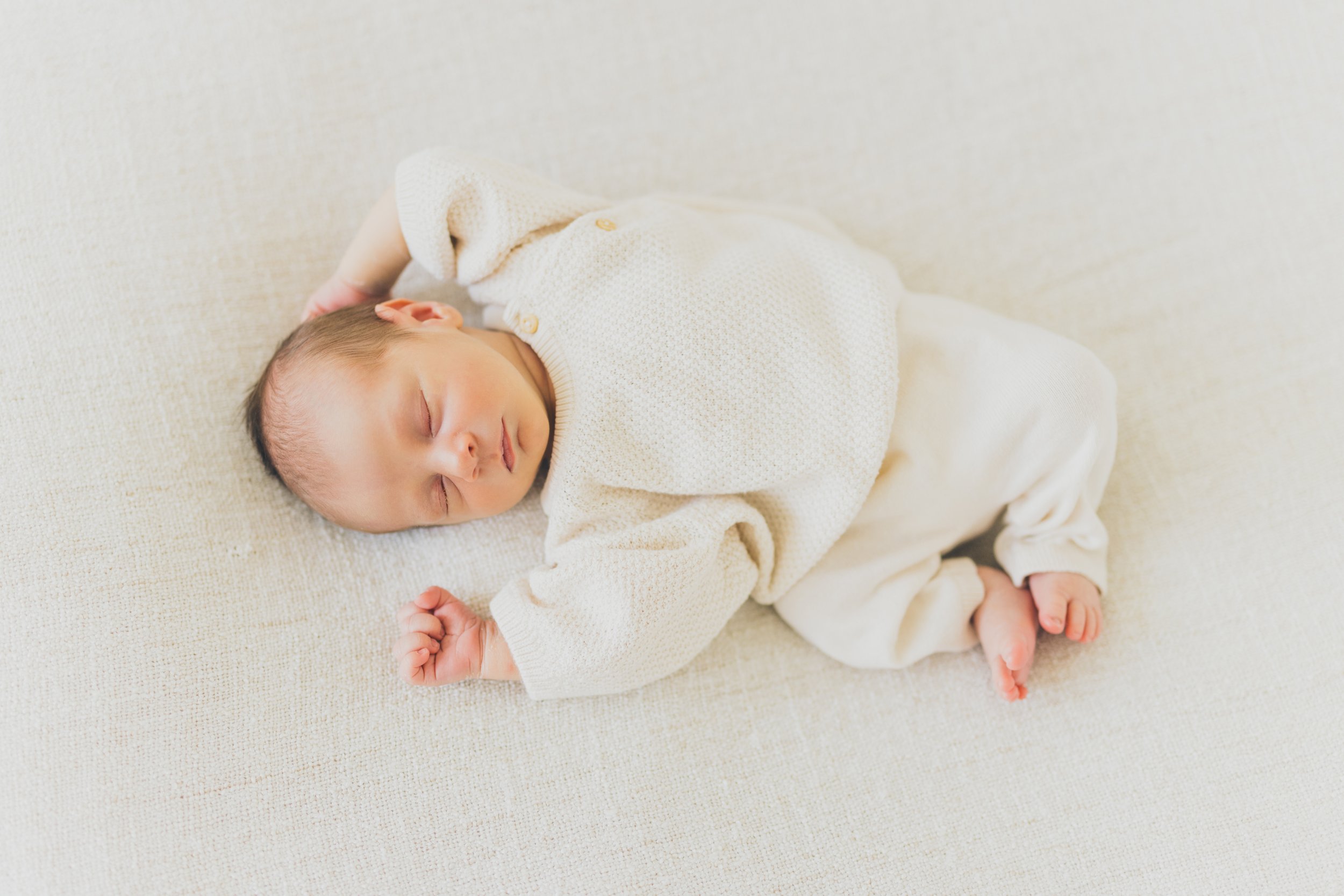  A newborn baby wearing cream coloured knitwear in RinkaDink Studio Belfast Northern Ireland. 