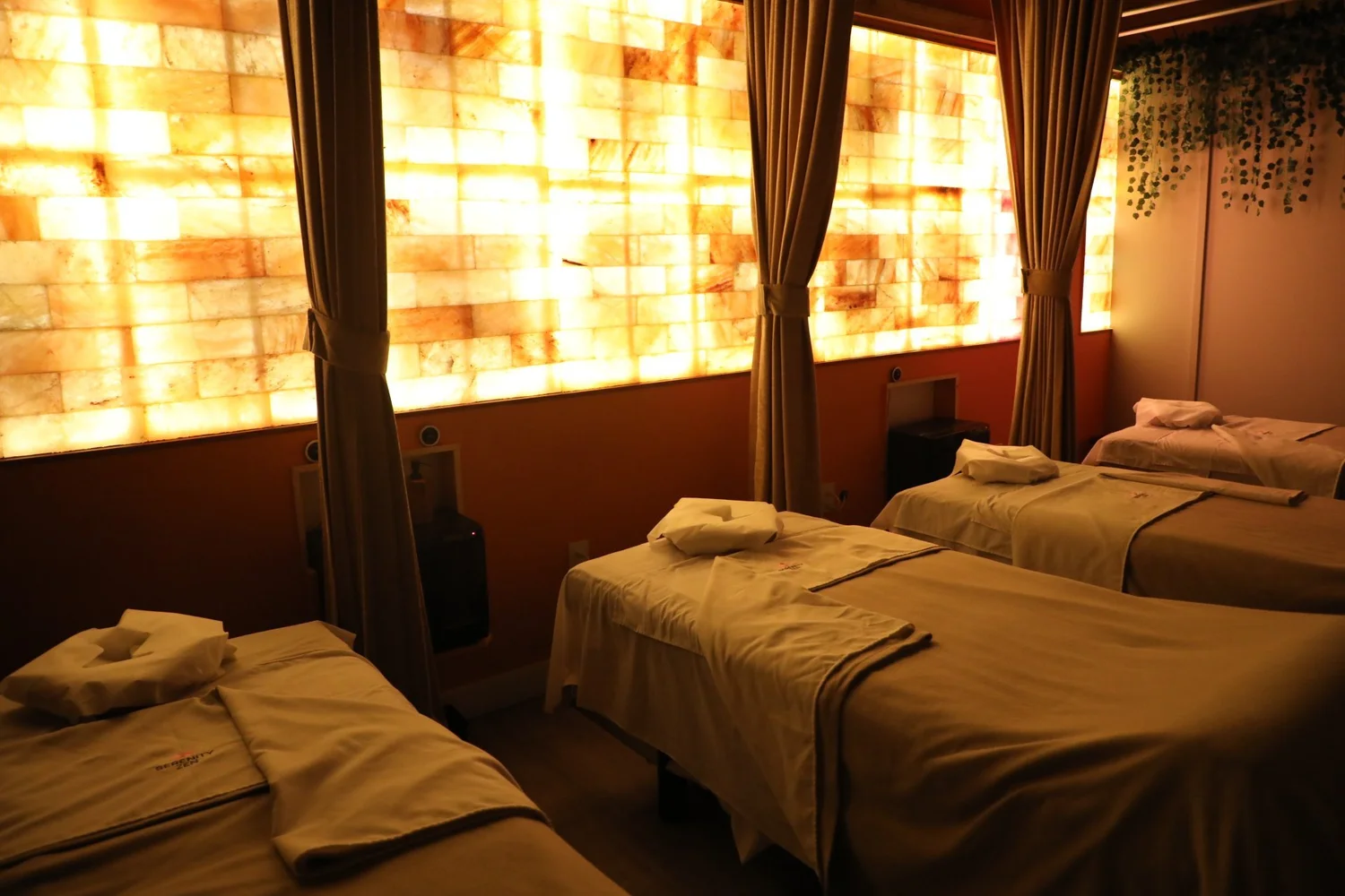 Curtained massage tables along a backlit salt wall at Serenity Zen Diamond Bar