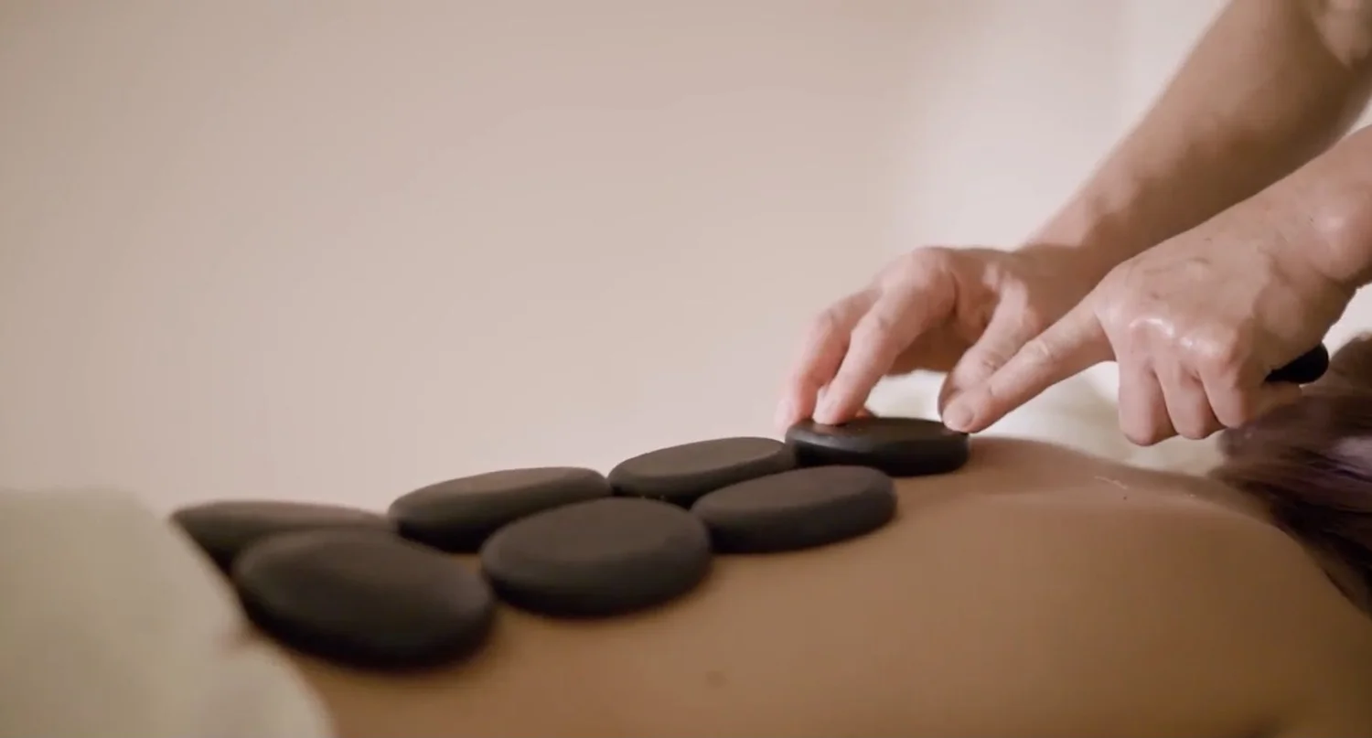 A therapist placing smooth black hot stones along a guest's back at Serenity Zen