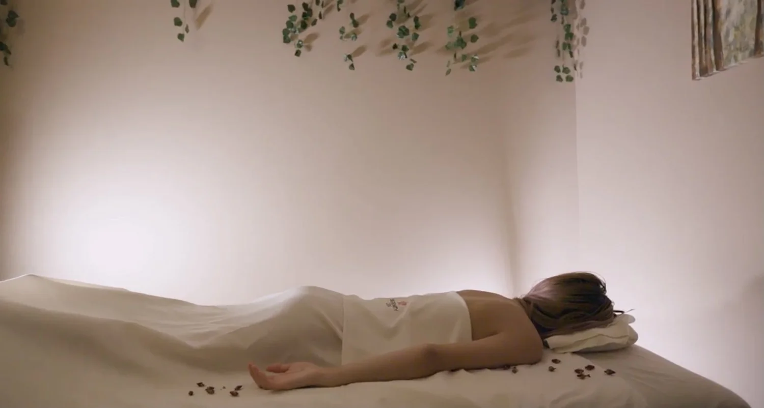 A guest resting face down under a white sheet on a massage table