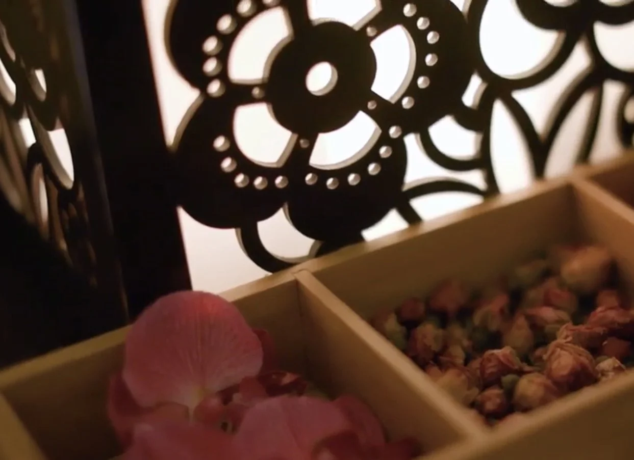 Dried rose buds in a wooden tray beside a carved screen at Serenity Zen