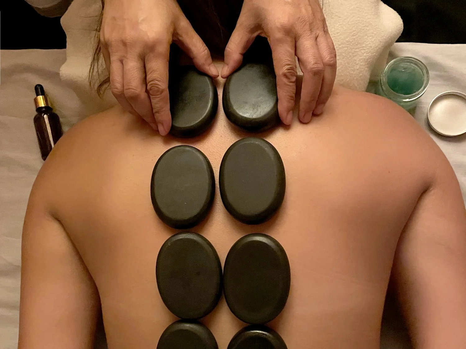 Smooth hot stones placed in two rows along a guest's back