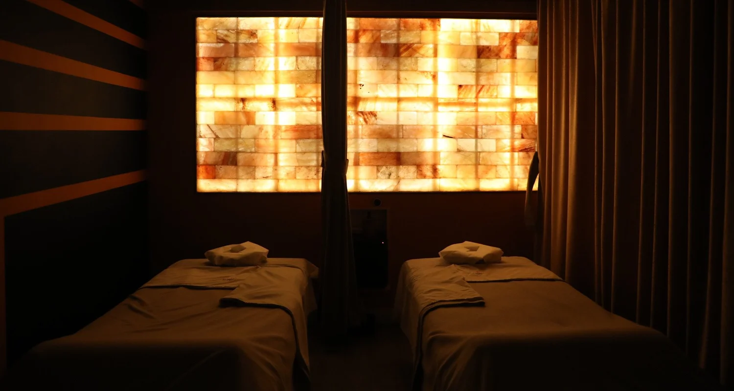 Two massage tables made up side by side under a backlit salt brick wall at Serenity Zen in Diamond Bar