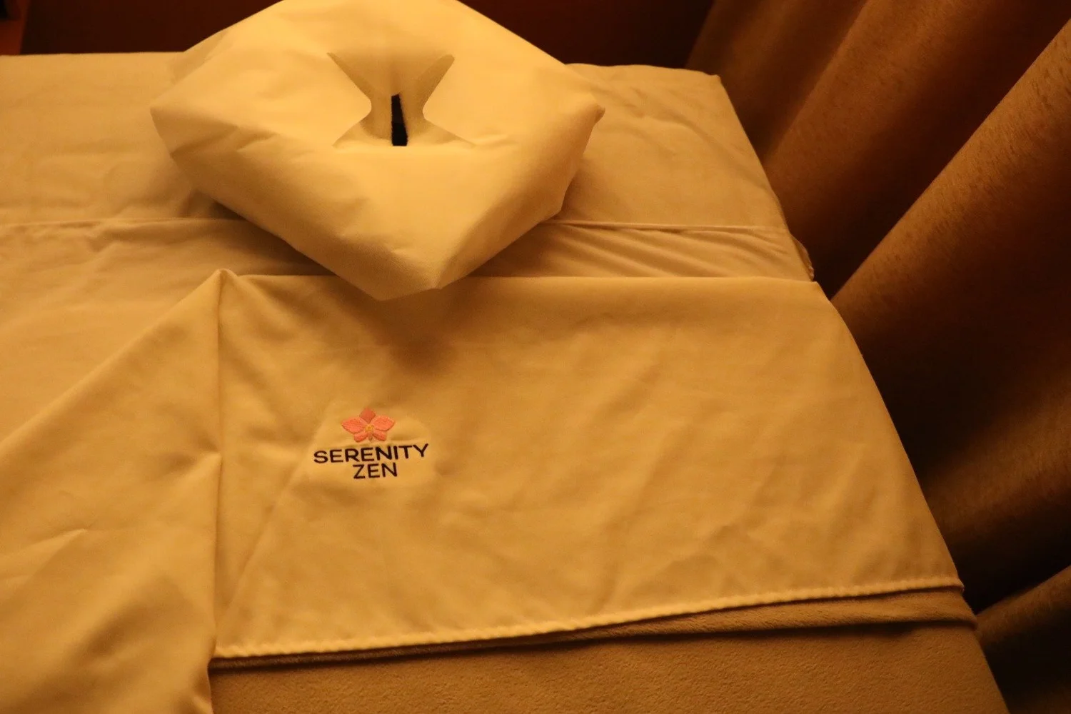 A massage table seen from above, with the orchid logo on the folded-back sheet, at Serenity Zen in Diamond Bar