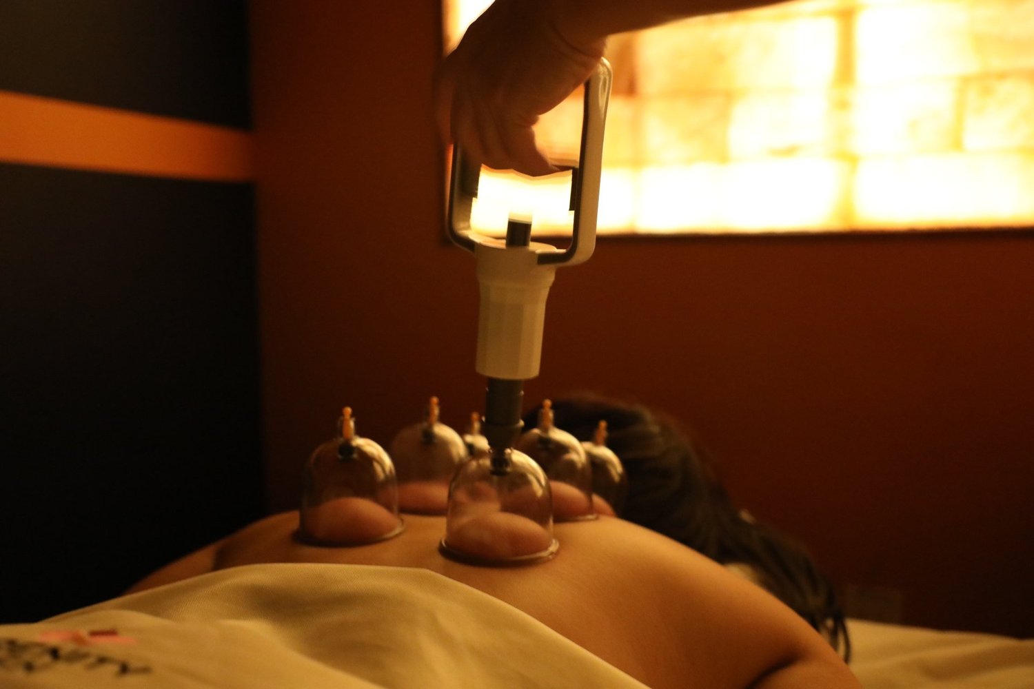 A therapist placing cups along a guest's back with a hand pump at Serenity Zen