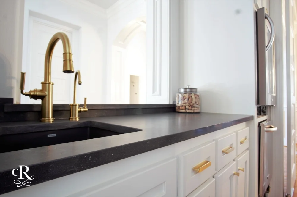 The fresh, new wet bar with dark charcoal quartz and brass plumbing fixtures. 