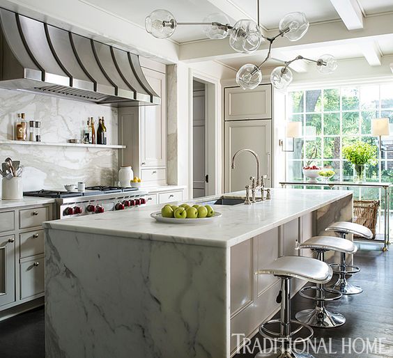Paloma Contreras via Traditional Home. A Waterfall Edge, Marble Counter With Matching Backsplash.
